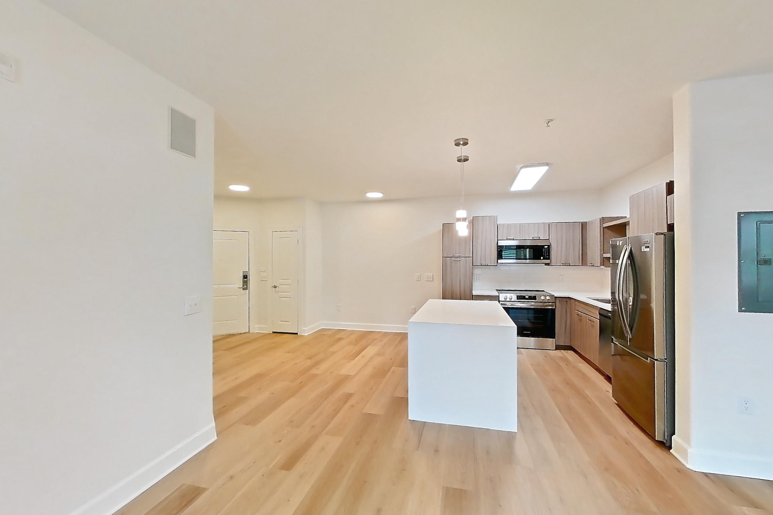 Living room with electric range, light countertops, light wood-finish flooring, oven/range, refrigerator, and stainless steel appliances, Apartment 206 at Talcott at Windermere