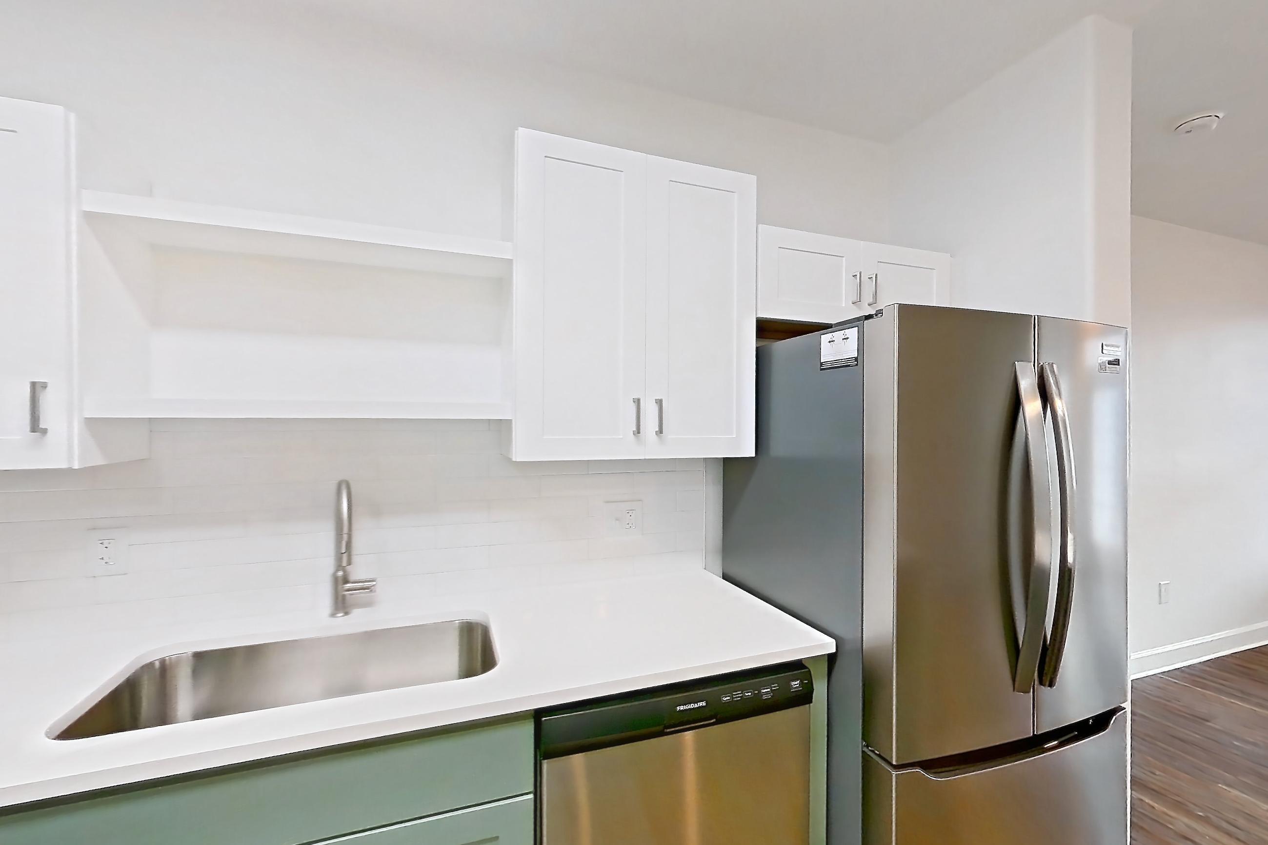 Kitchen with dark wood-finish flooring, dishwasher, electric range, light countertops, light stone countertops, oven/range, refrigerator, and stainless steel appliances, Apartment 208 at Talcott at Windermere