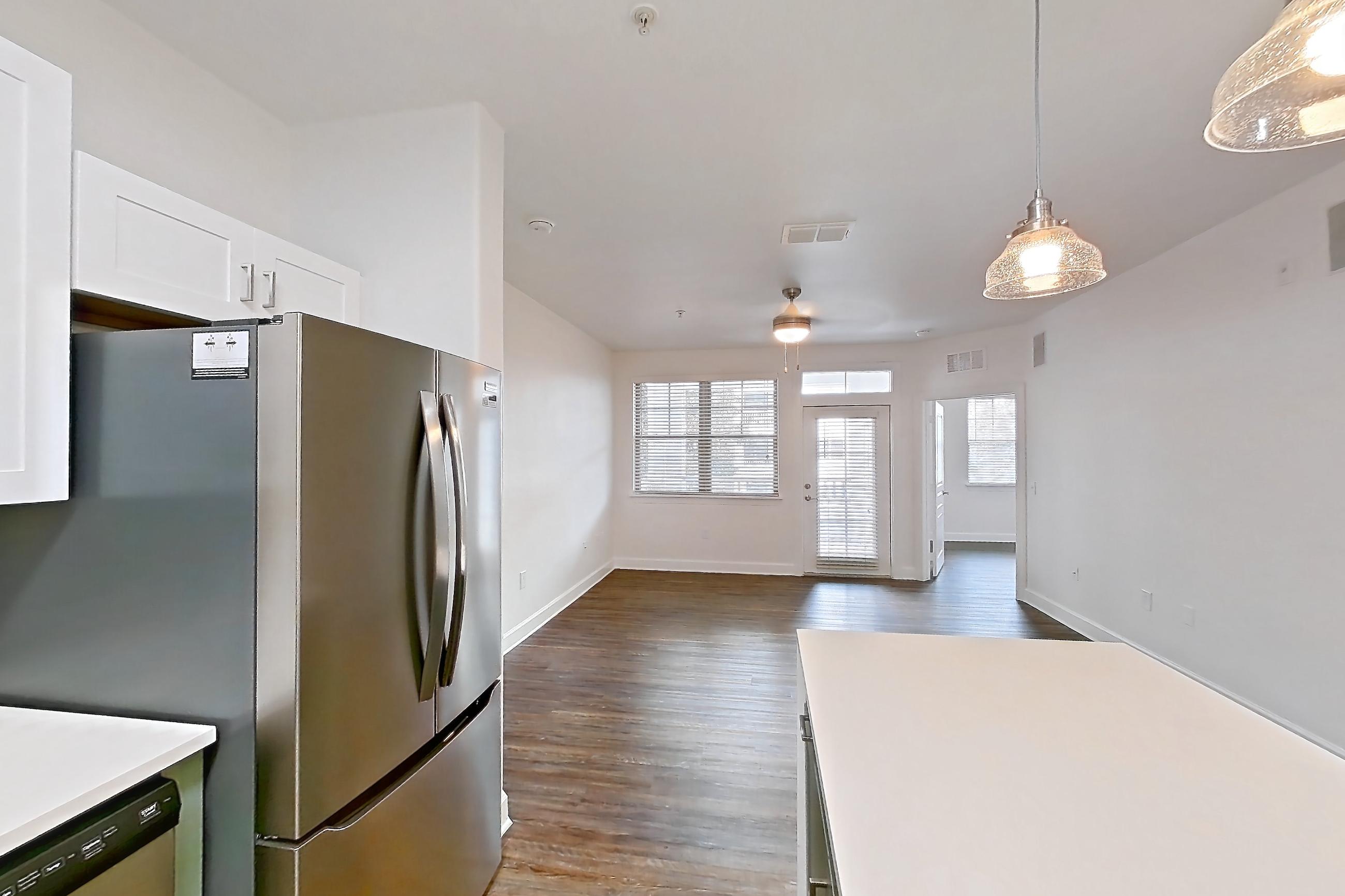 Kitchen with dark wood-finish flooring, dishwasher, electric range, light countertops, light stone countertops, oven/range, refrigerator, and stainless steel appliances, Apartment 208 at Talcott at Windermere