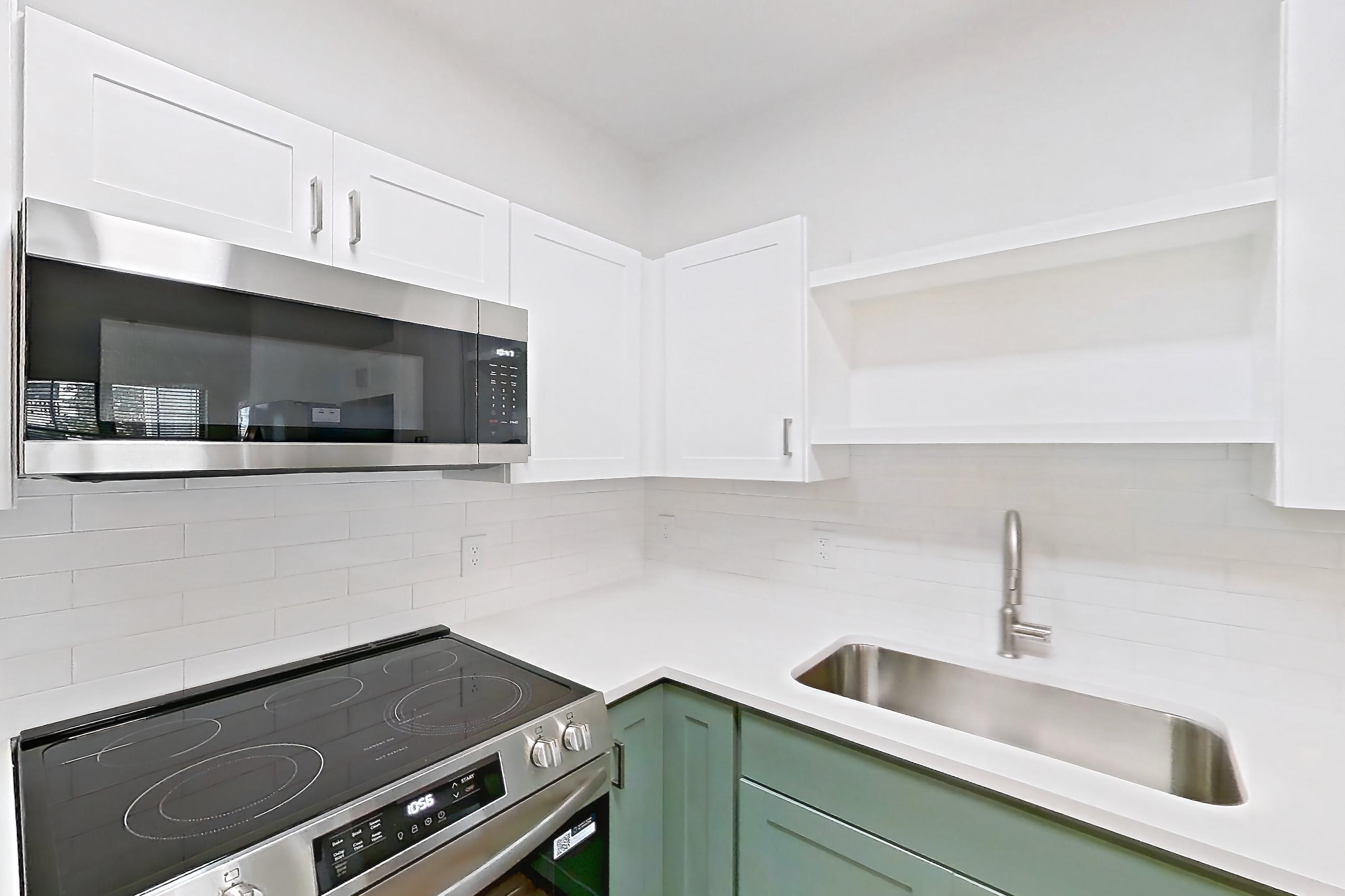 Kitchen with dark wood-finish flooring, dishwasher, electric range, light countertops, light stone countertops, oven/range, refrigerator, and stainless steel appliances, Apartment 208 at Talcott at Windermere