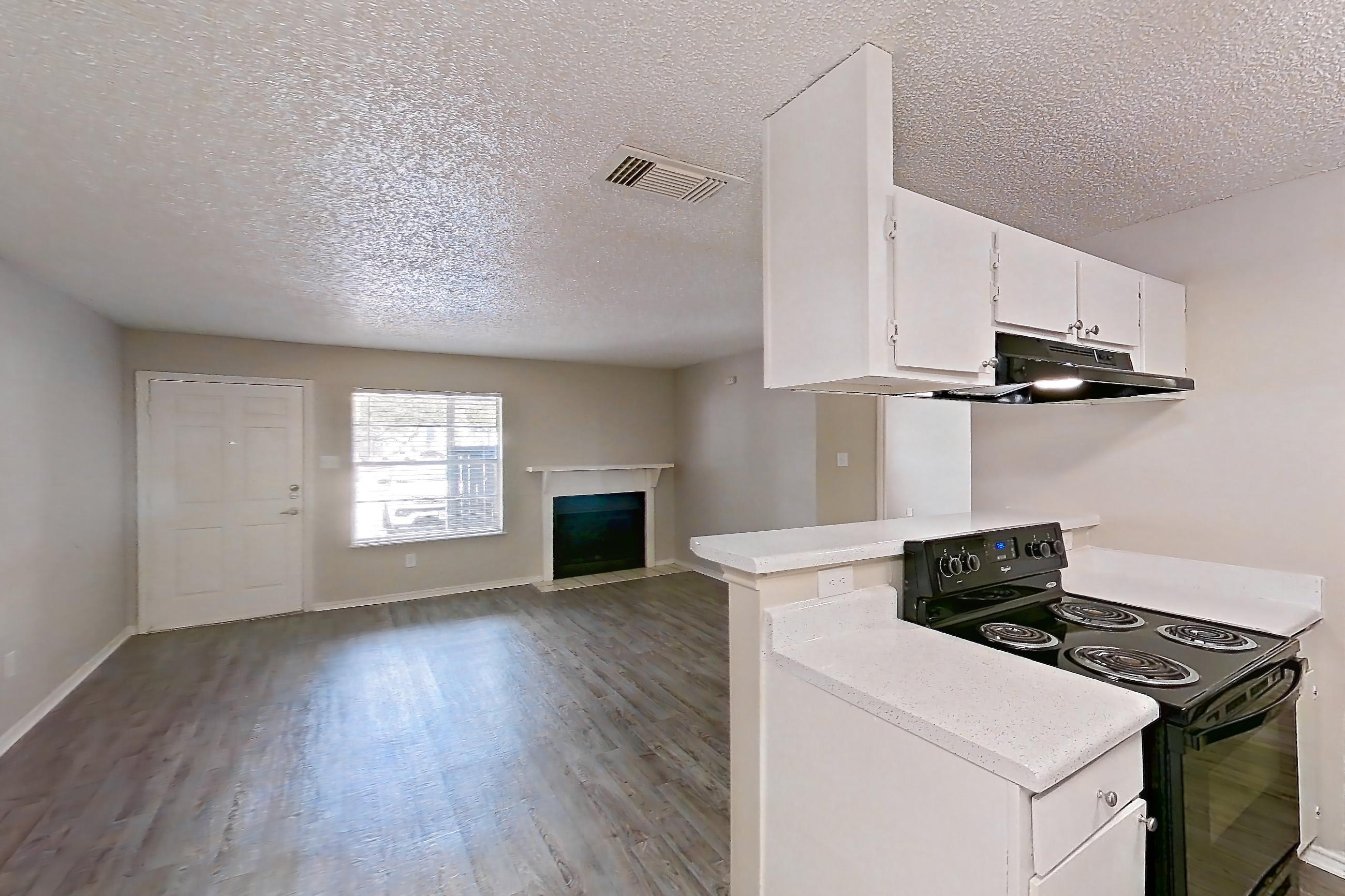 Dining room with black appliances, dishwasher, electric range, fireplace, light countertops, light wood-finish flooring, oven/range, range hood, and refrigerator, Apartment 1605P at The Carmel