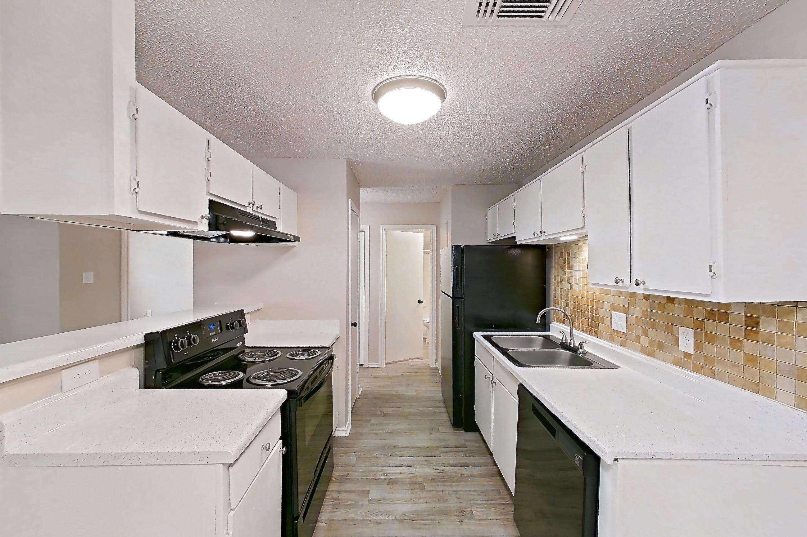Dining room with black appliances, dishwasher, electric range, fireplace, light countertops, light wood-finish flooring, oven/range, range hood, and refrigerator, Apartment 1605P at The Carmel