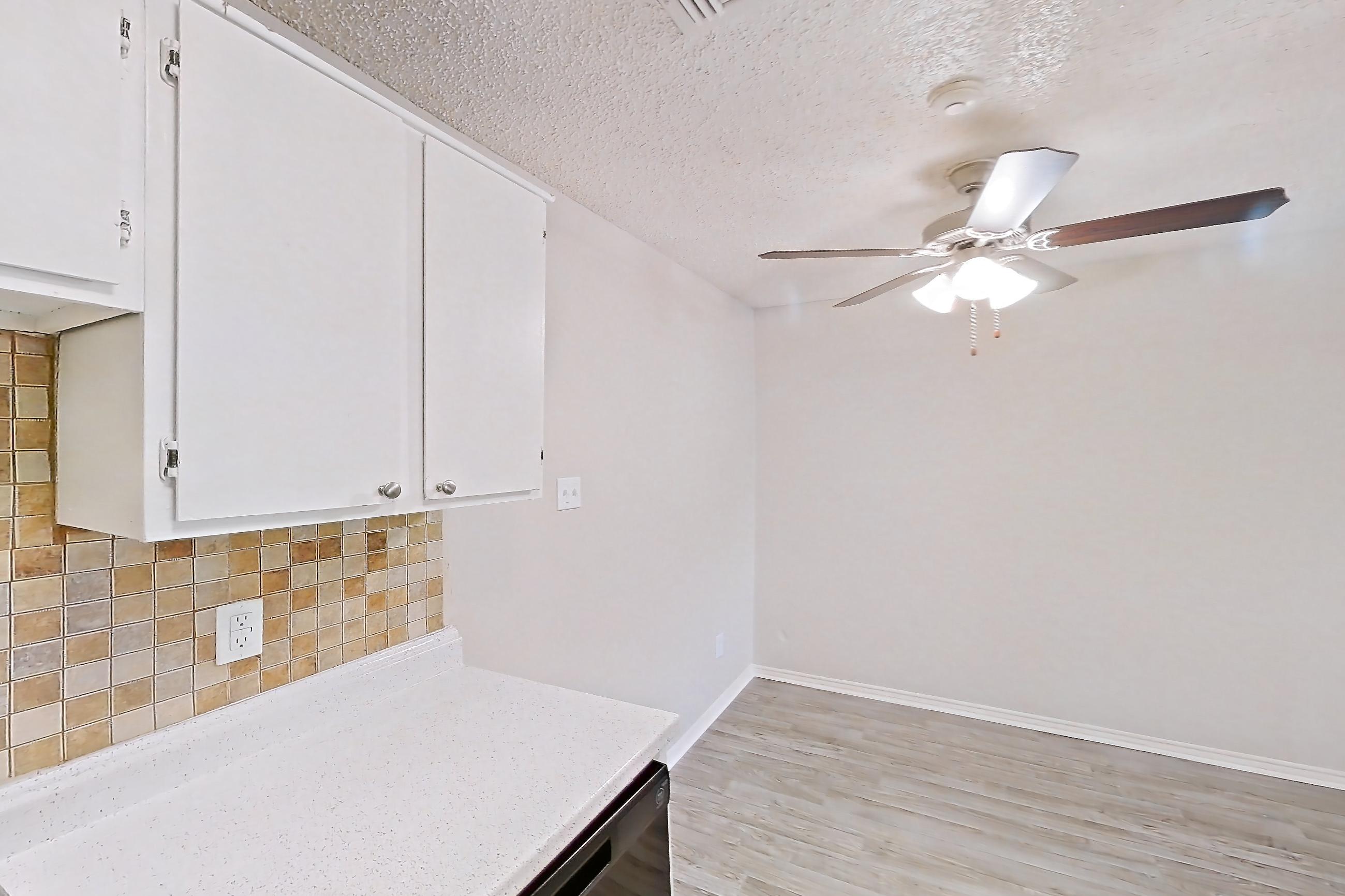Kitchen with black appliances, dishwasher, electric range, light countertops, light stone countertops, light wood-finish flooring, oven/range, range hood, and refrigerator, Apartment 1605P at The Carmel