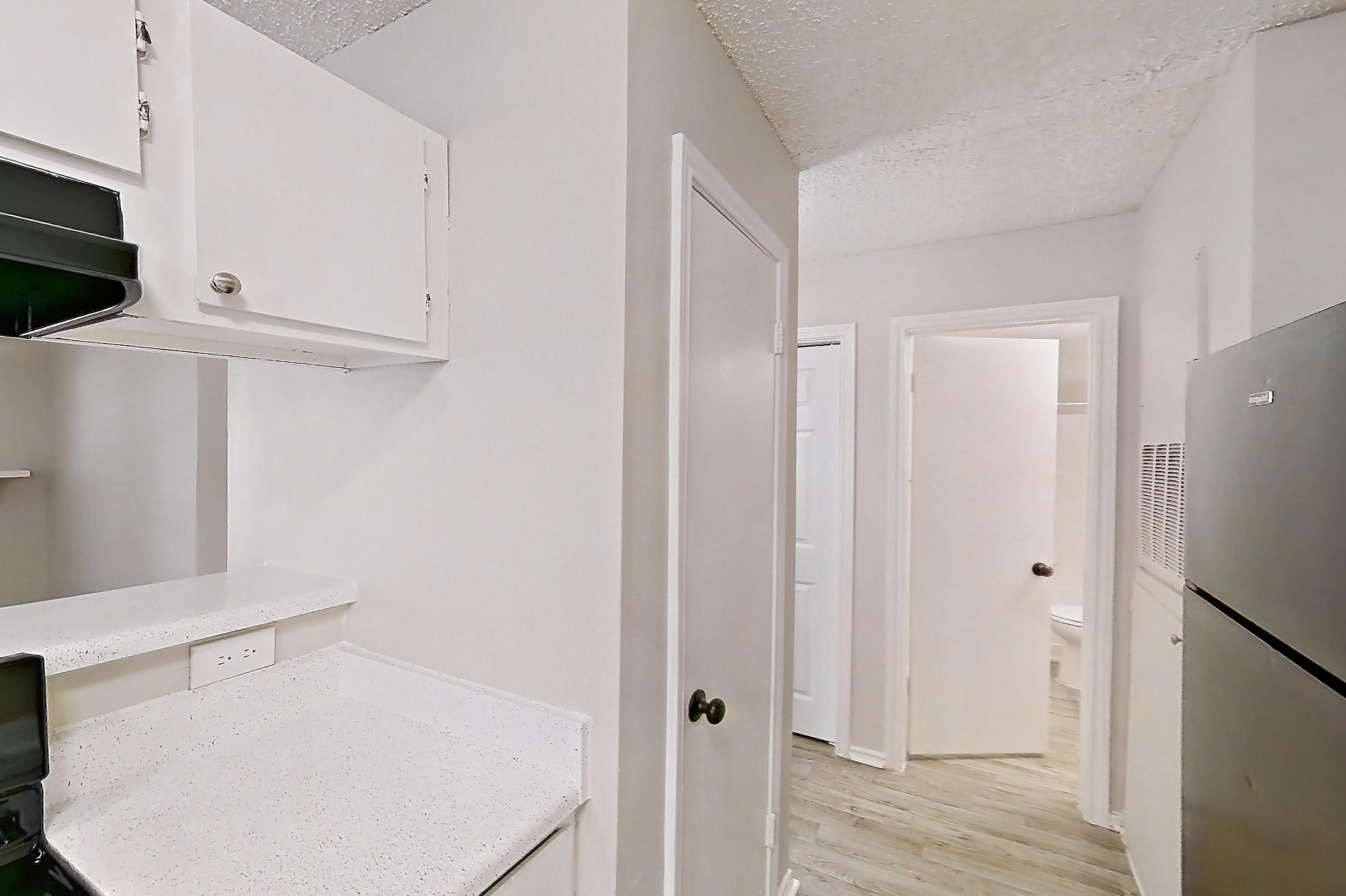 Kitchen with black appliances, dishwasher, electric range, light countertops, light stone countertops, light wood-finish flooring, oven/range, range hood, and refrigerator, Apartment 1605P at The Carmel