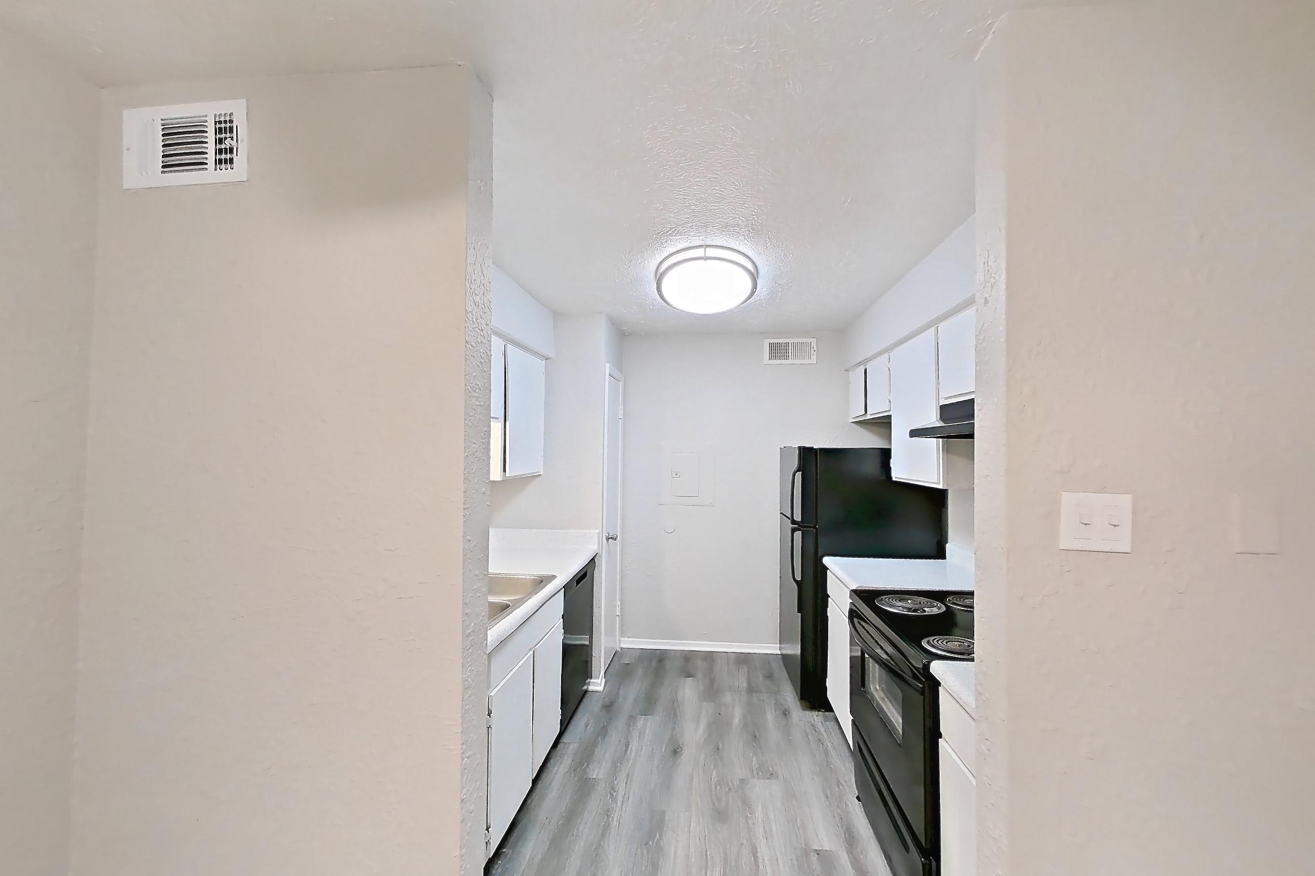 Dining room with black appliances, dishwasher, electric range, light countertops, light wood-finish flooring, oven/range, refrigerator, and stainless steel appliances, Apartment 118B at The Carmel