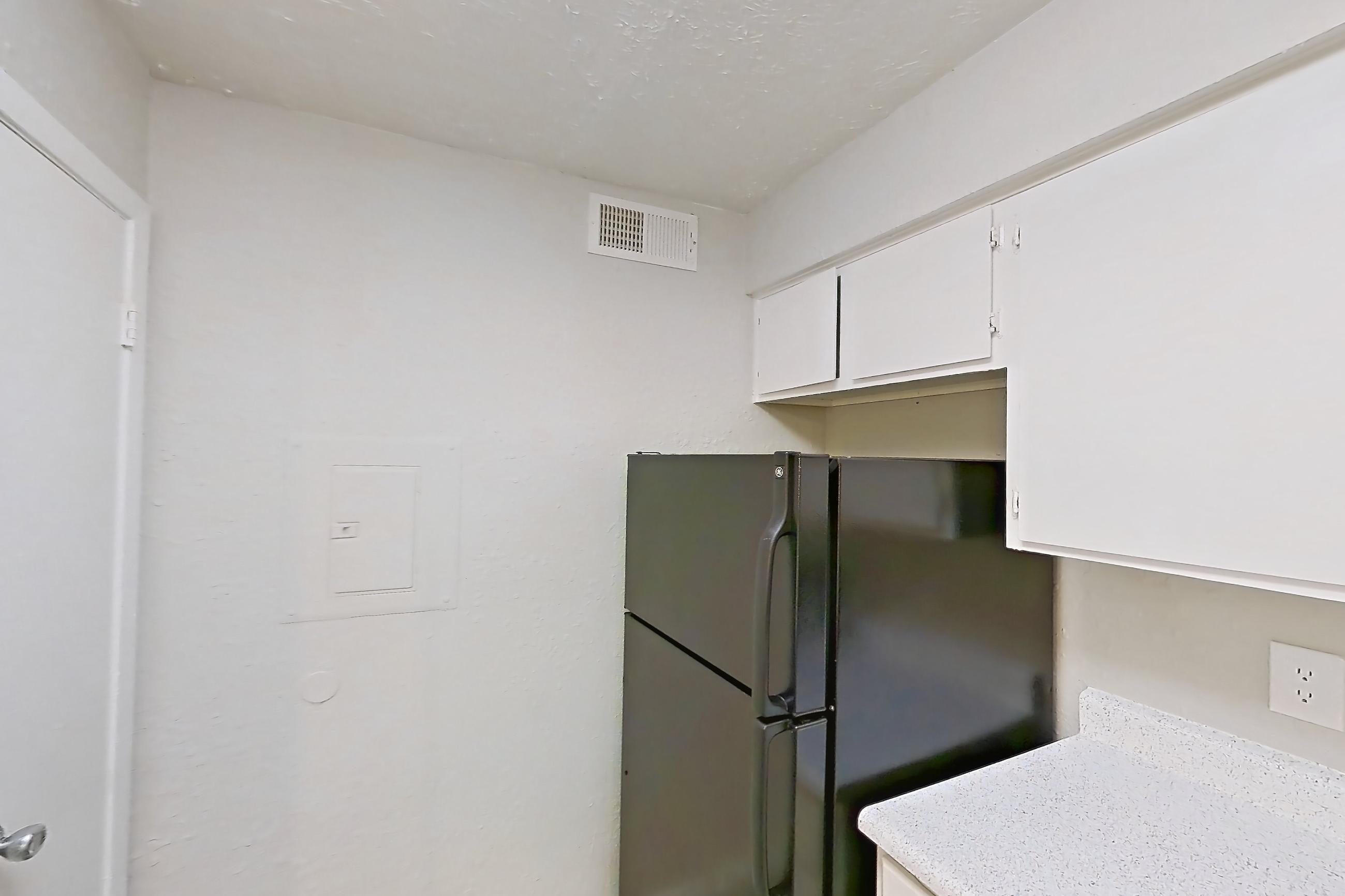 Kitchen with black appliances, electric range, light countertops, light stone countertops, light wood-finish flooring, oven/range, and refrigerator, Apartment 118B at The Carmel
