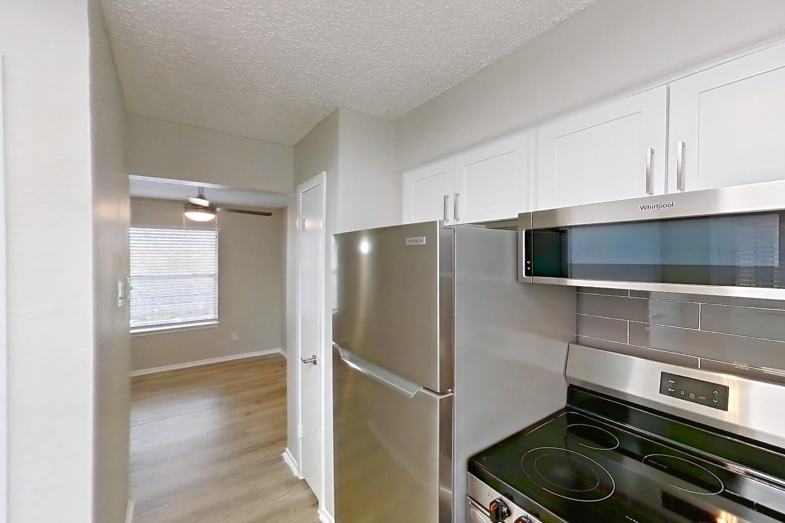 Kitchen with electric range, light countertops, light wood-finish flooring, oven/range, refrigerator, and stainless steel appliances, Apartment 1104 at Bella Vista
