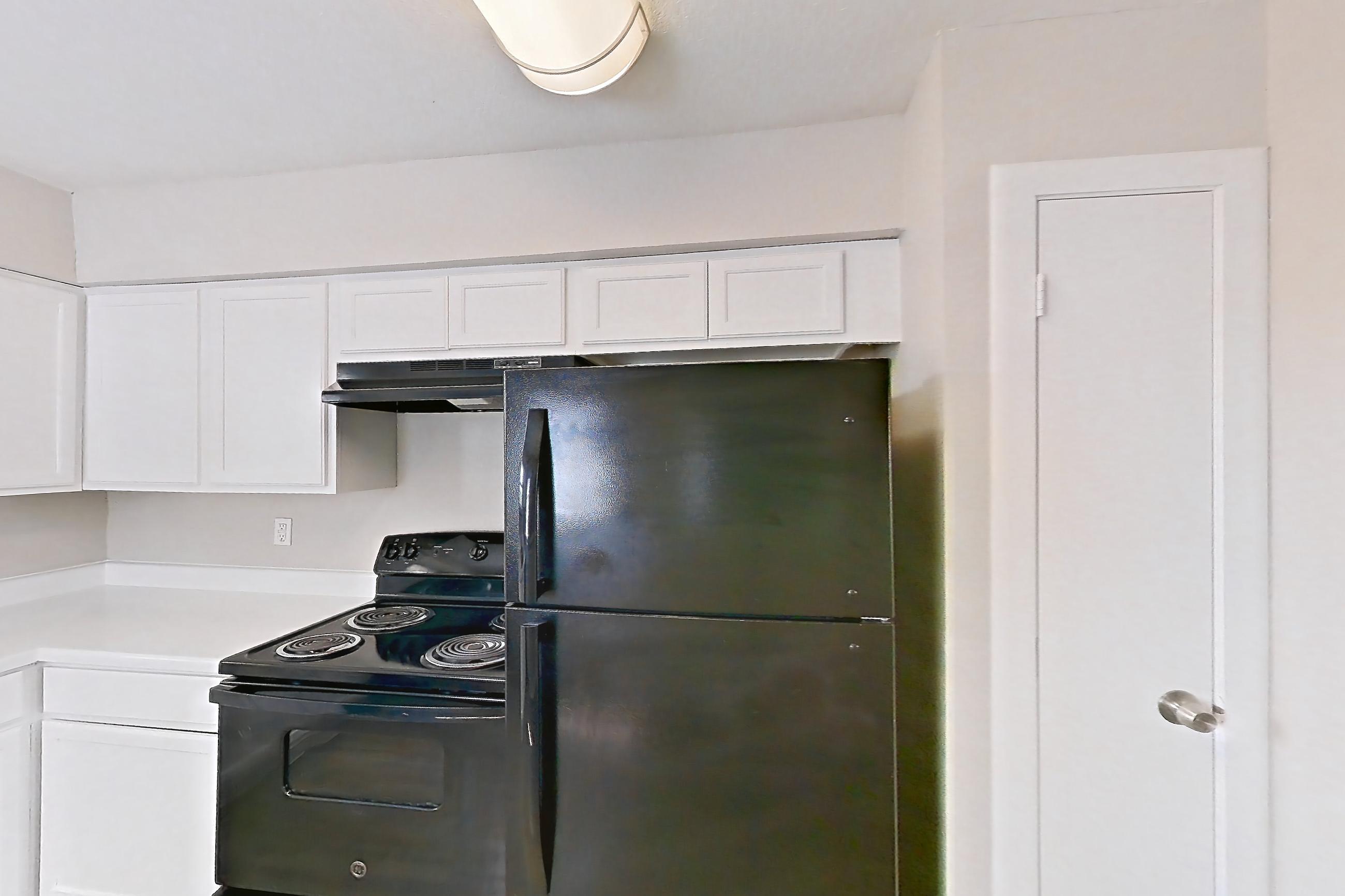 Kitchen with black appliances, dishwasher, electric range, light countertops, light wood-finish flooring, oven/range, and refrigerator, Apartment 2902 at Bella Vista