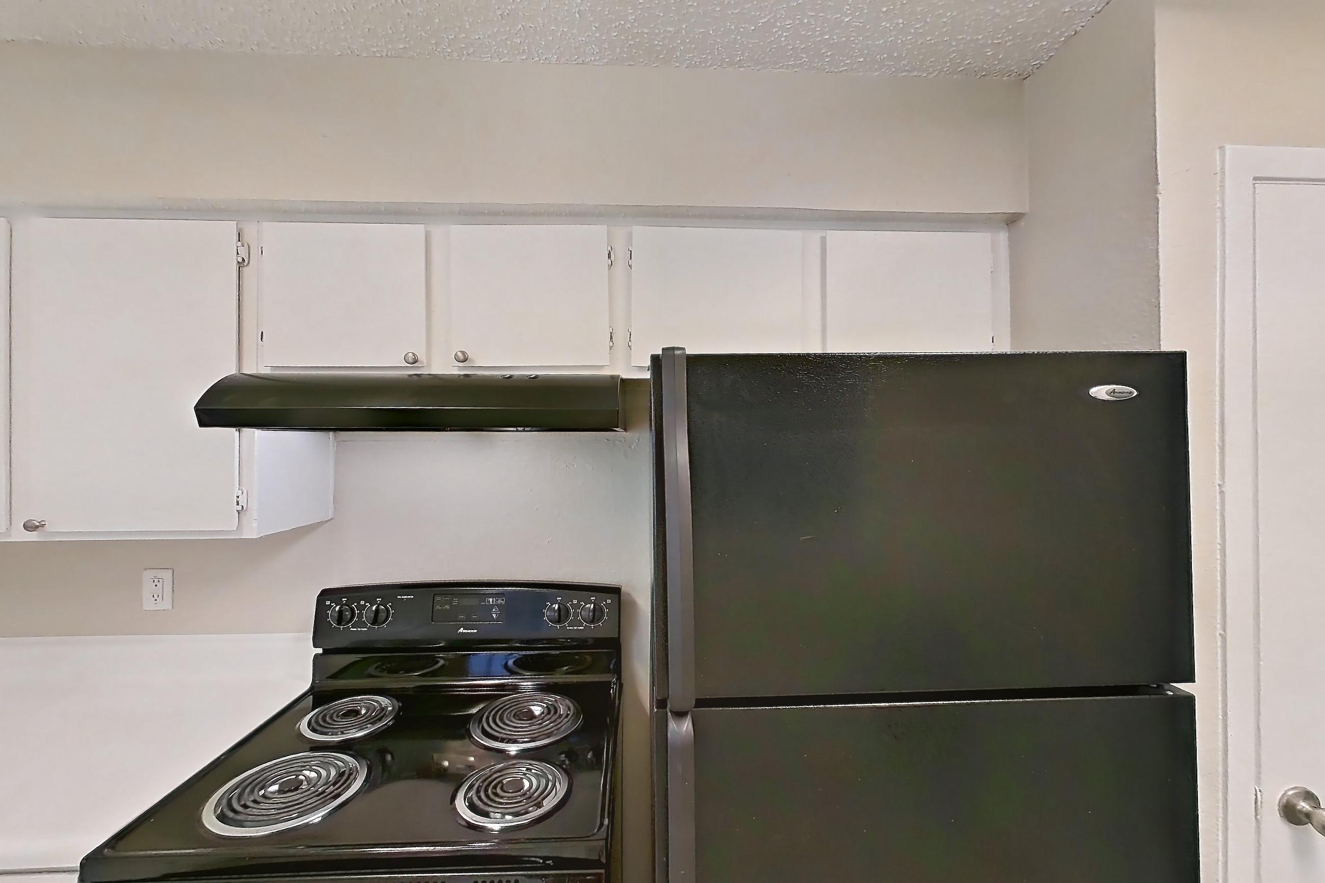 Kitchen with black appliances, dishwasher, electric range, light countertops, light wood-finish flooring, oven/range, and refrigerator, Apartment 4104 at Bella Vista