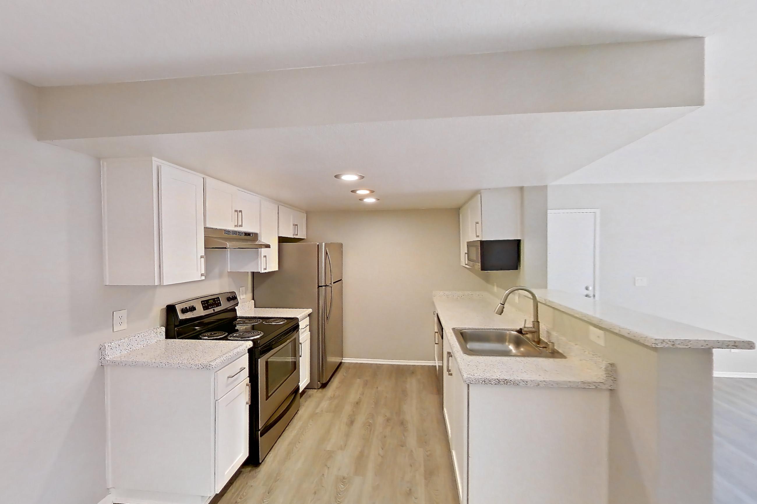 Dining room with in-unit laundry, light stone countertops, light wood-finish flooring, oven/range, refrigerator, and stainless steel appliances, Apartment Y-05 at Avana Rancho Cucamonga