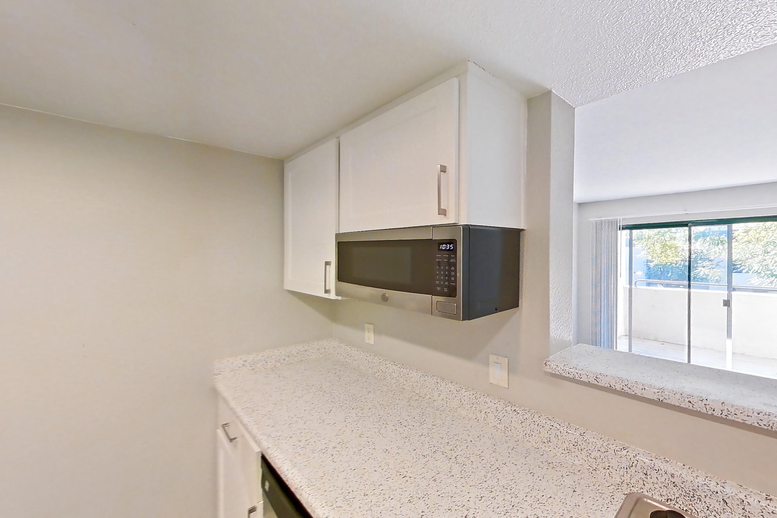 Kitchen with dishwasher, in-unit laundry, light stone countertops, light wood-finish flooring, microwave, oven/range, and stainless steel appliances, Apartment Y-05 at Avana Rancho Cucamonga