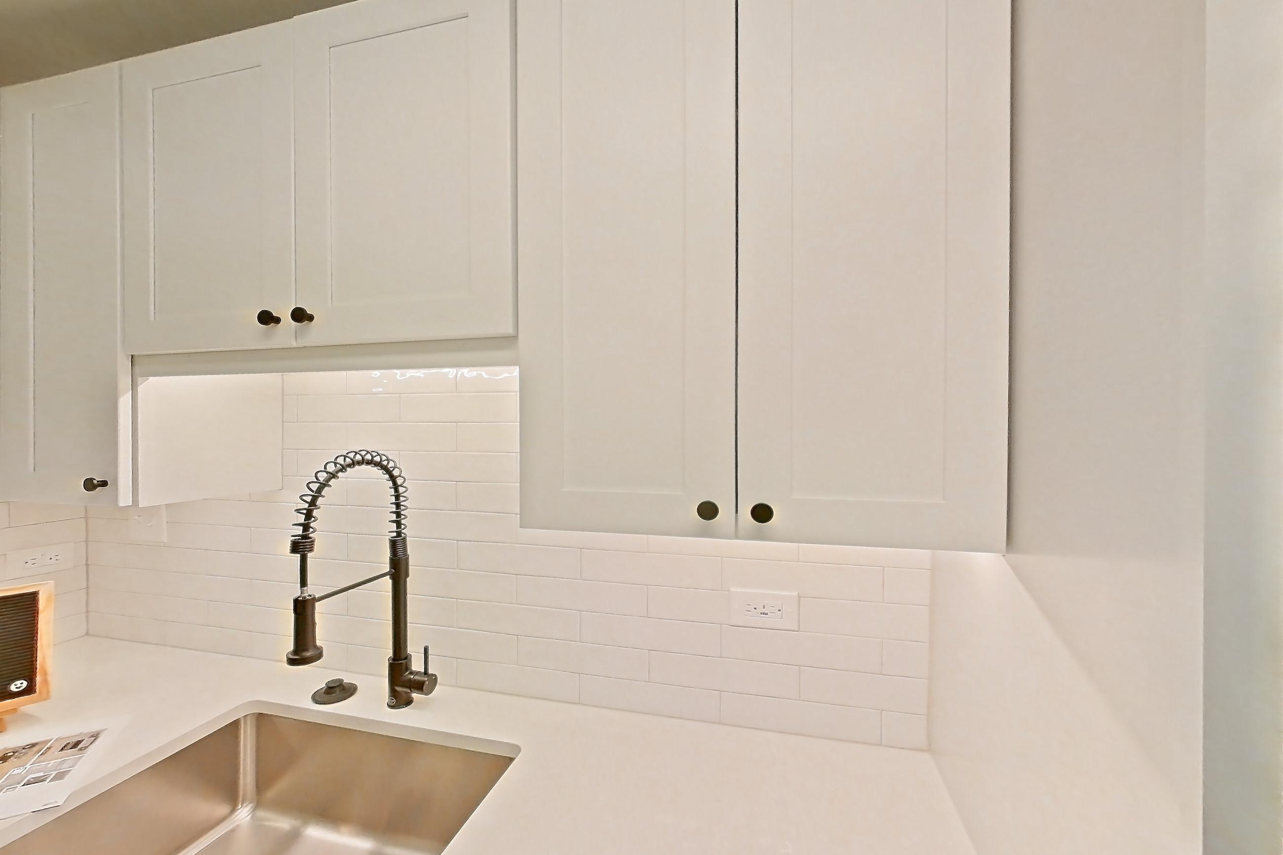 Kitchen with dark wood-finish flooring, electric range, light countertops, light stone countertops, microwave, oven/range, and stainless steel appliances, Apartment 409 at Cortland at McLean