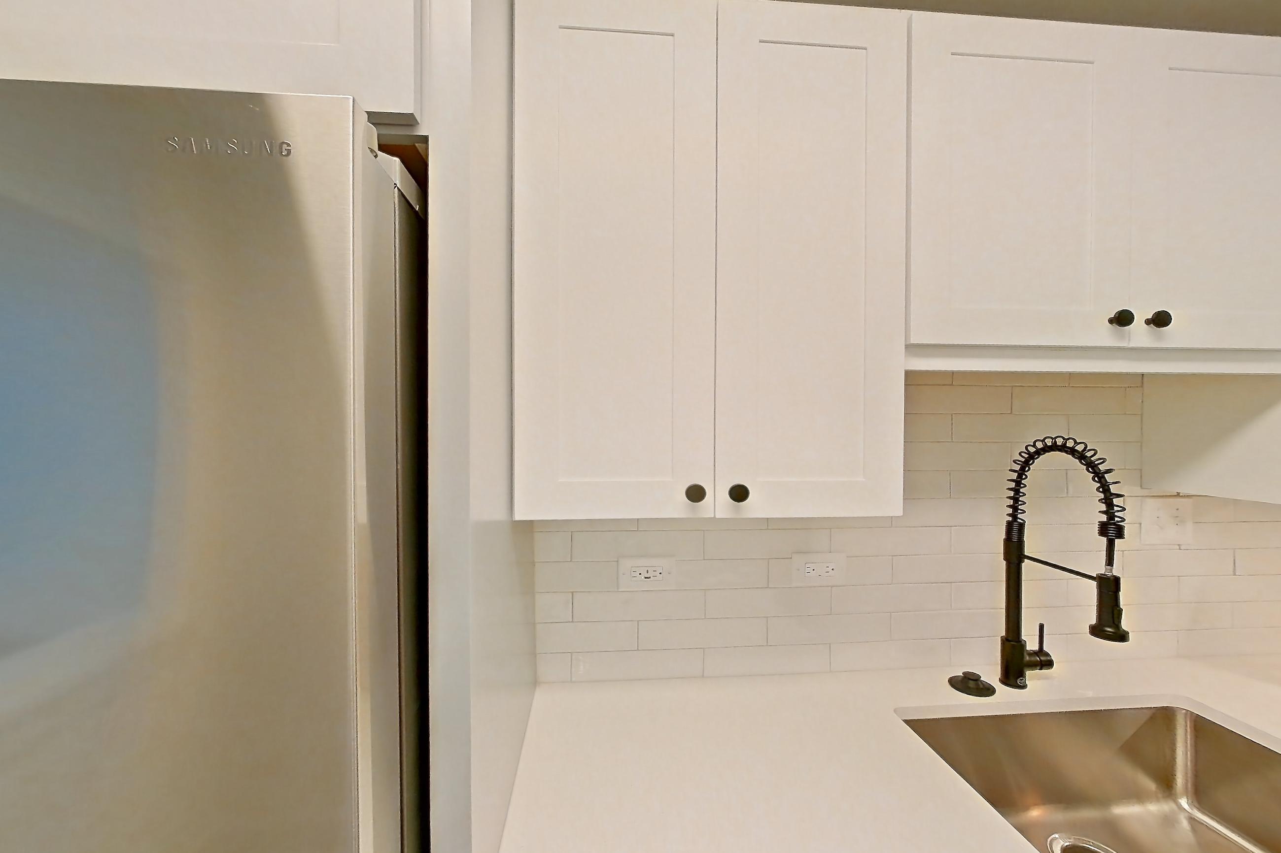 Kitchen with dark wood-finish flooring, dishwasher, electric range, light countertops, light stone countertops, microwave, oven/range, and stainless steel appliances, Apartment 415 at Cortland at McLean