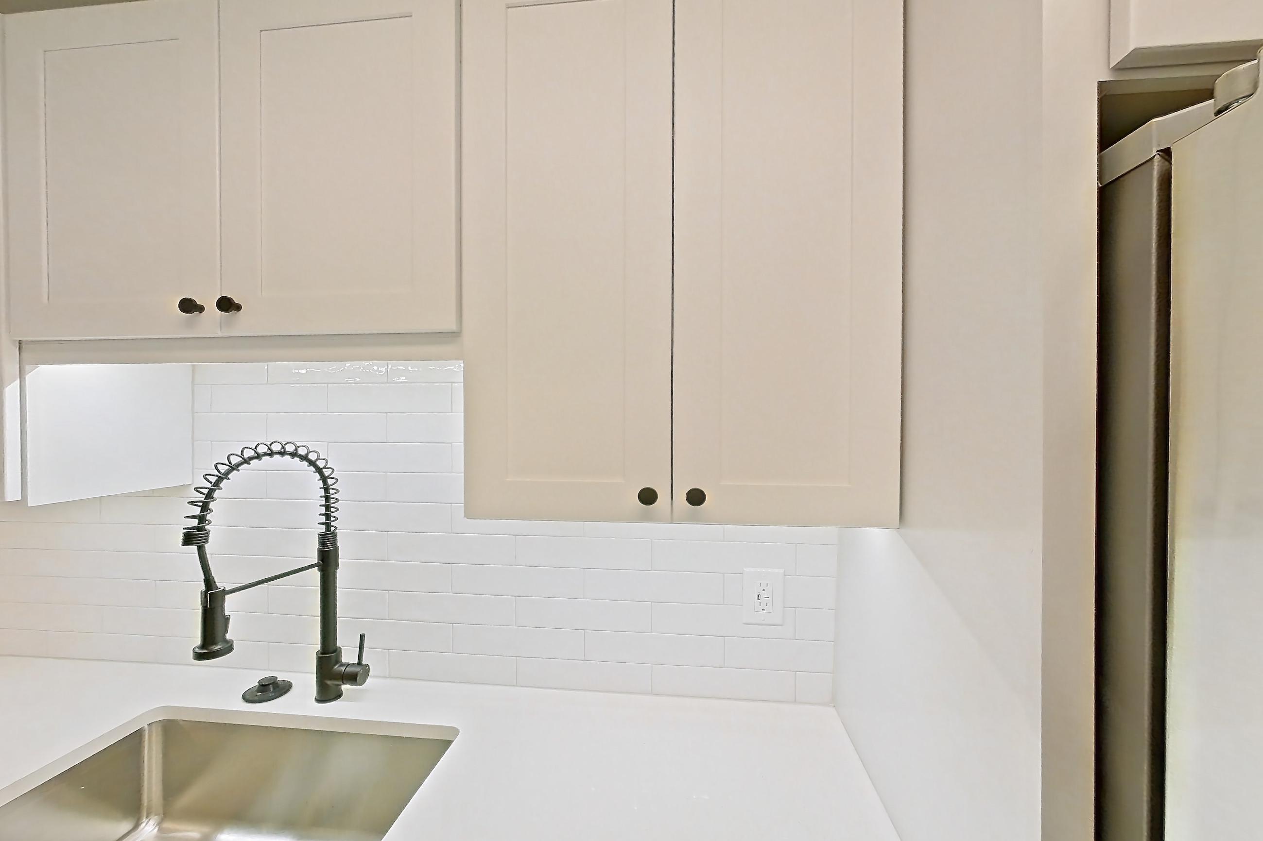 Kitchen with dark wood-finish flooring, dishwasher, electric range, light countertops, light stone countertops, microwave, oven/range, and stainless steel appliances, Apartment 909 at Cortland at McLean