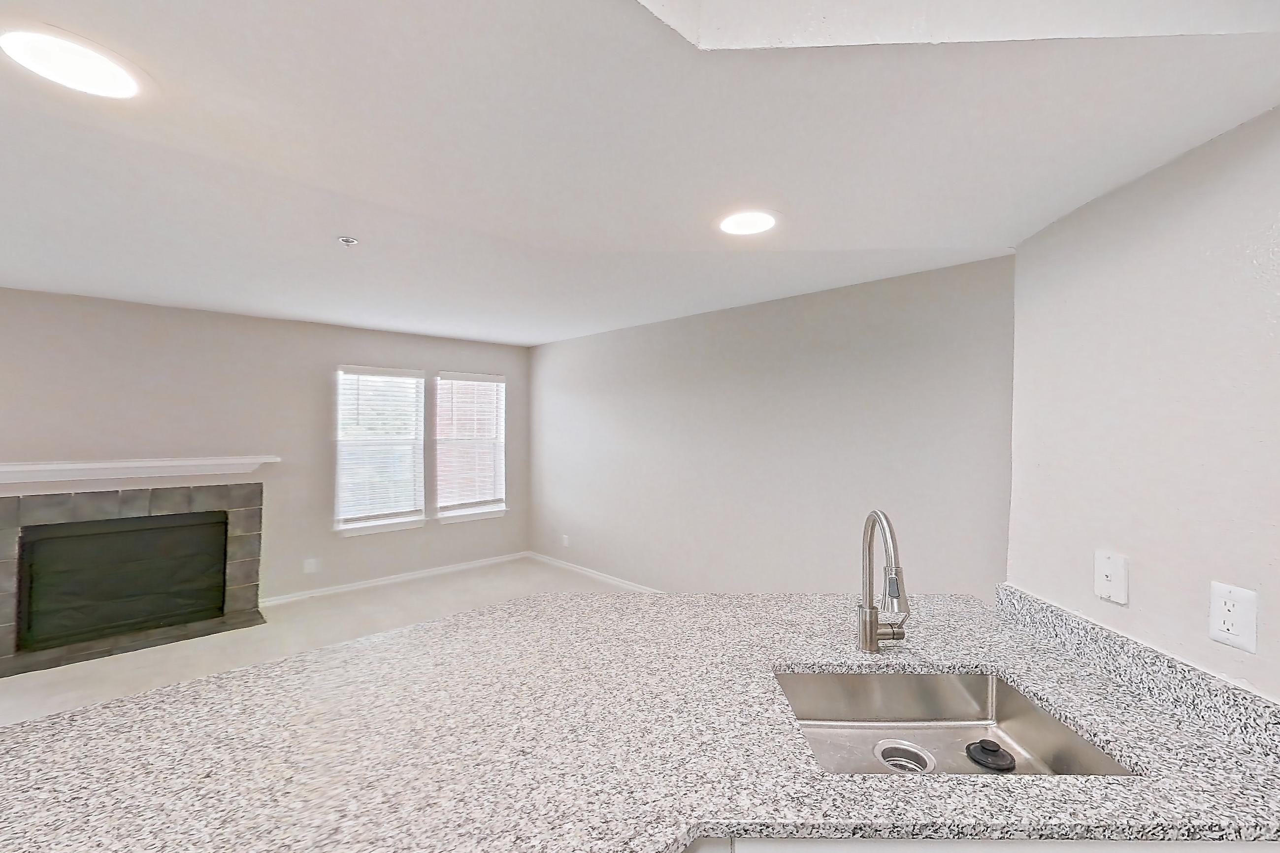Kitchen with dishwasher, electric range, fireplace, light countertops, light stone countertops, light wood-finish flooring, microwave, oven/range, refrigerator, stainless steel appliances, and tile fireplace, Apartment 4206 at Cortland Van Dorn
