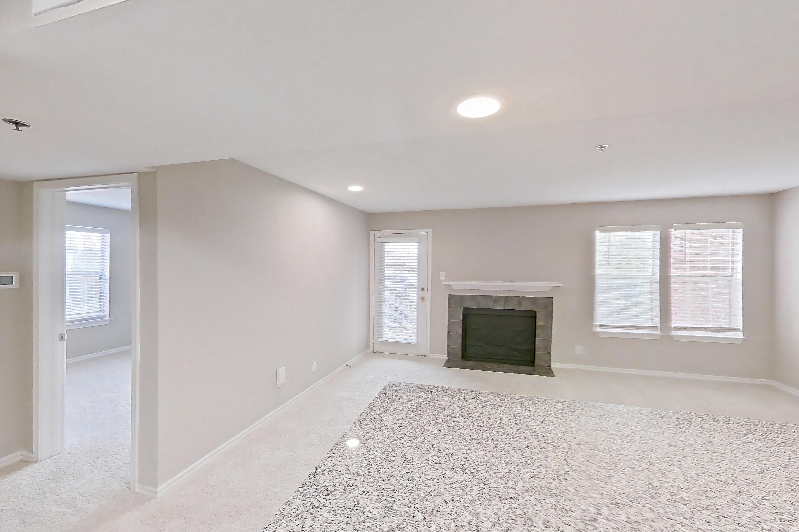 Kitchen with dishwasher, electric range, fireplace, light countertops, light stone countertops, light wood-finish flooring, microwave, oven/range, refrigerator, stainless steel appliances, and tile fireplace, Apartment 4206 at Cortland Van Dorn