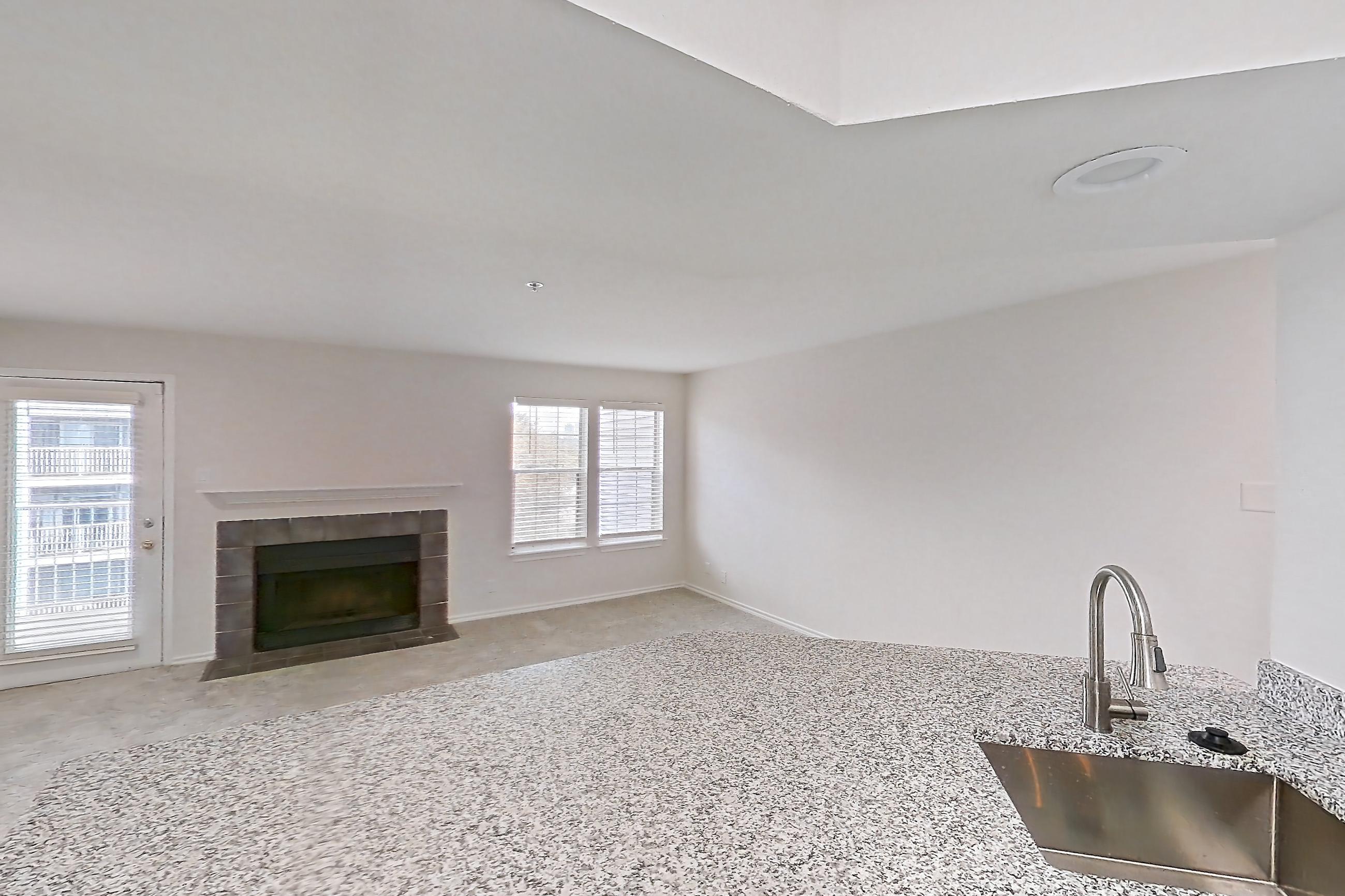 Kitchen with dishwasher, electric range, fireplace, light countertops, light stone countertops, light wood-finish flooring, microwave, oven/range, refrigerator, stainless steel appliances, and tile fireplace, Apartment 7305 at Cortland Van Dorn