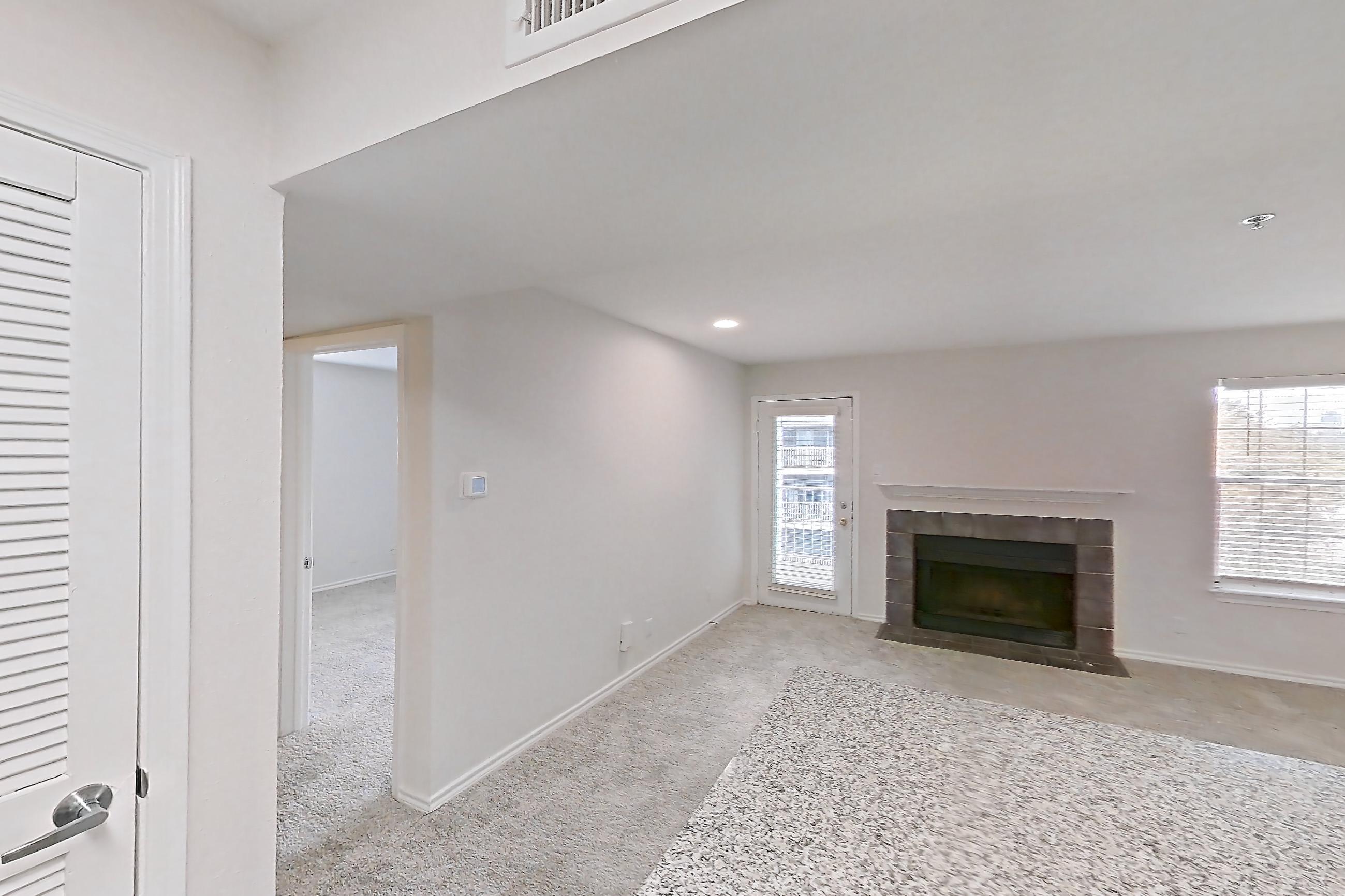 Kitchen with dishwasher, electric range, fireplace, light countertops, light stone countertops, light wood-finish flooring, microwave, oven/range, refrigerator, stainless steel appliances, and tile fireplace, Apartment 7305 at Cortland Van Dorn