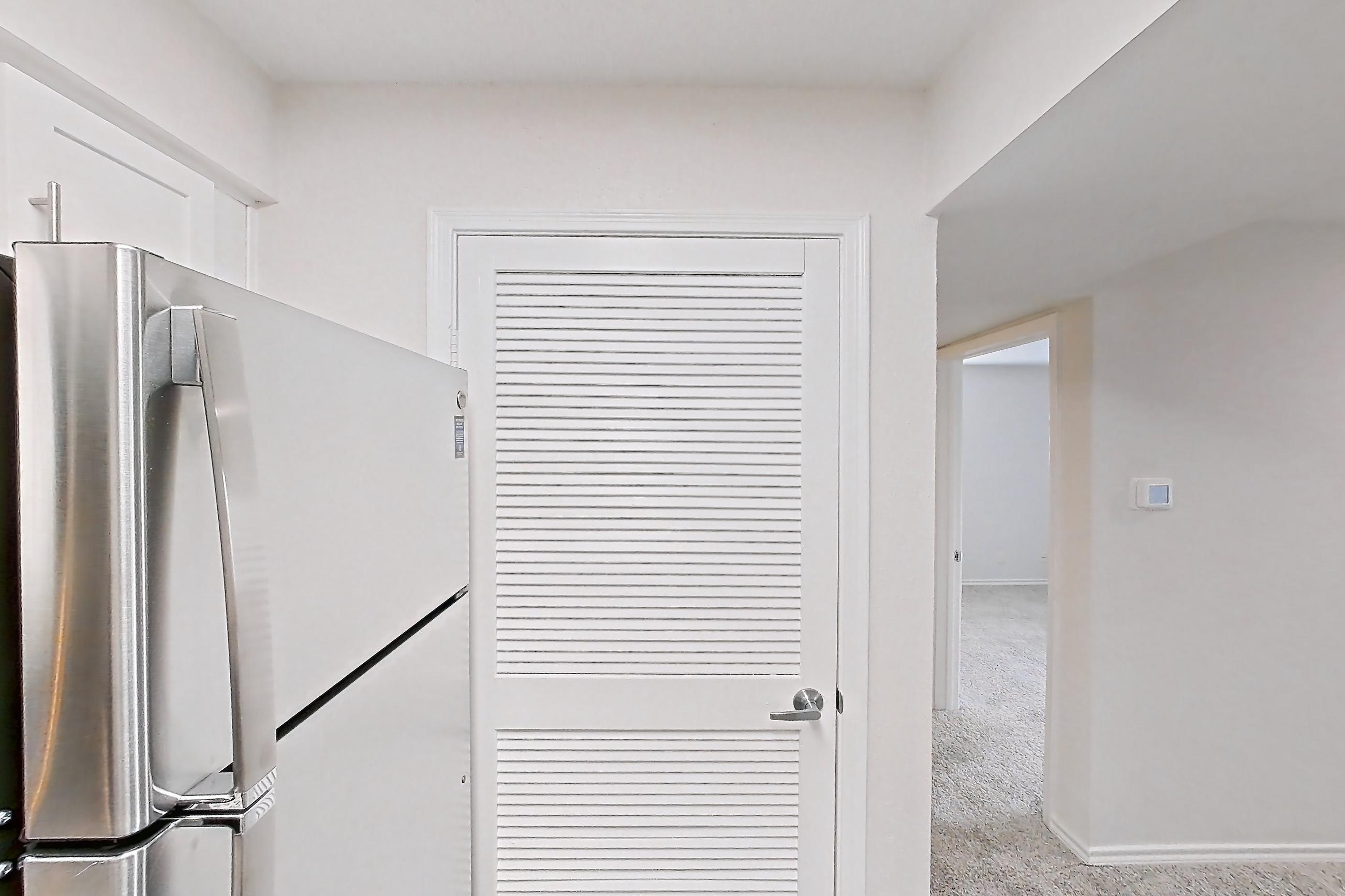 Kitchen with dishwasher, electric range, fireplace, light countertops, light stone countertops, light wood-finish flooring, microwave, oven/range, refrigerator, stainless steel appliances, and tile fireplace, Apartment 7305 at Cortland Van Dorn