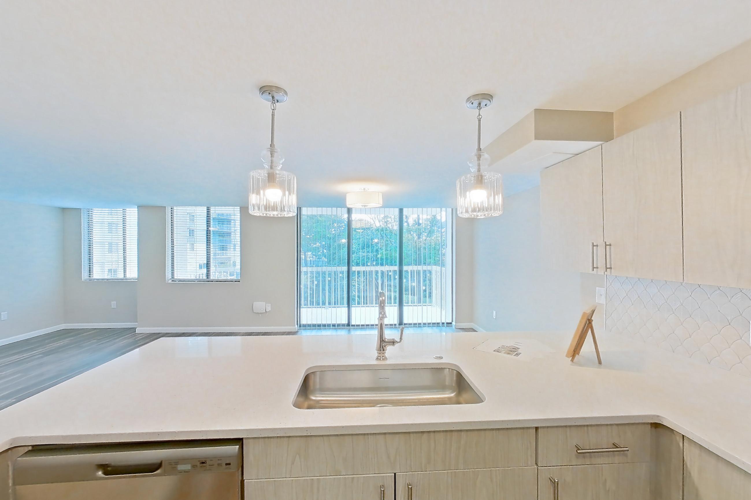 Kitchen with dishwasher, electric range, light countertops, light stone countertops, light wood-finish flooring, microwave, oven/range, refrigerator, and stainless steel appliances, Apartment 219 at Cortland at McLean