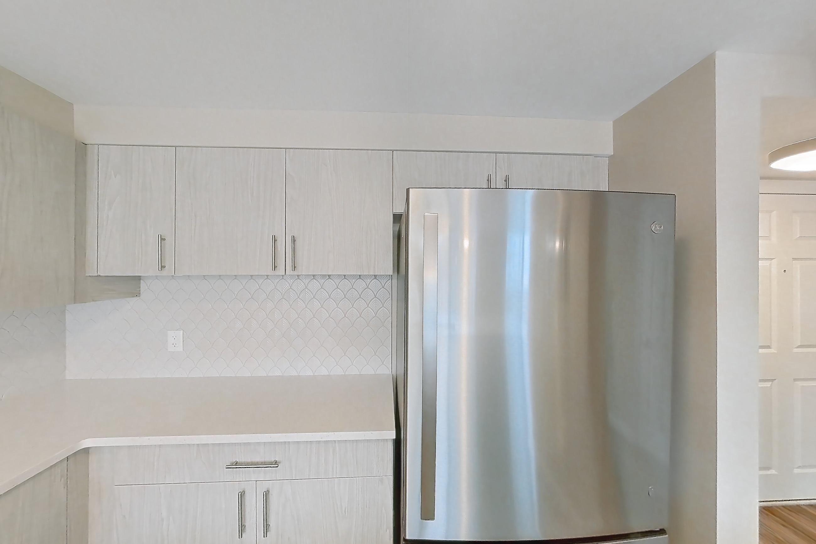 Kitchen with dishwasher, electric range, light countertops, light stone countertops, light wood-finish flooring, microwave, oven/range, refrigerator, and stainless steel appliances, Apartment 219 at Cortland at McLean