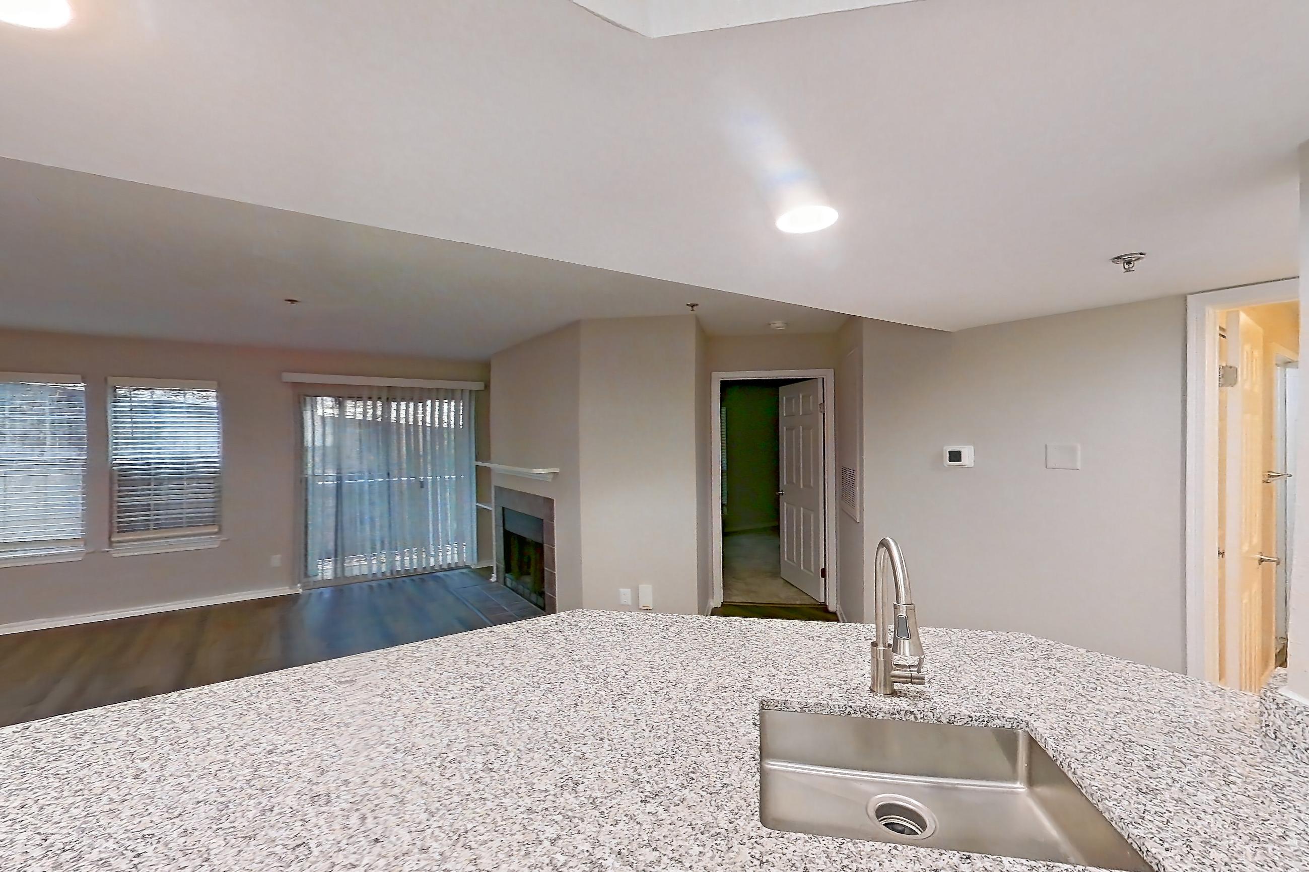 Kitchen with dark wood-finish flooring, dishwasher, electric range, fireplace, light countertops, light stone countertops, light wood-finish flooring, microwave, oven/range, and stainless steel appliances, Apartment 3110 at Cortland Van Dorn