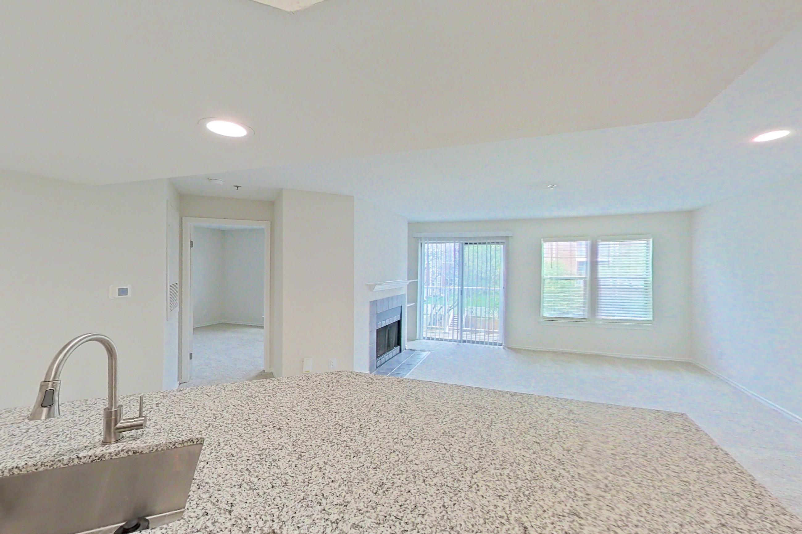 Kitchen with dishwasher, electric range, fireplace, light countertops, light stone countertops, light wood-finish flooring, microwave, oven/range, refrigerator, stainless steel appliances, and white appliances, Apartment 5117 at Cortland Van Dorn