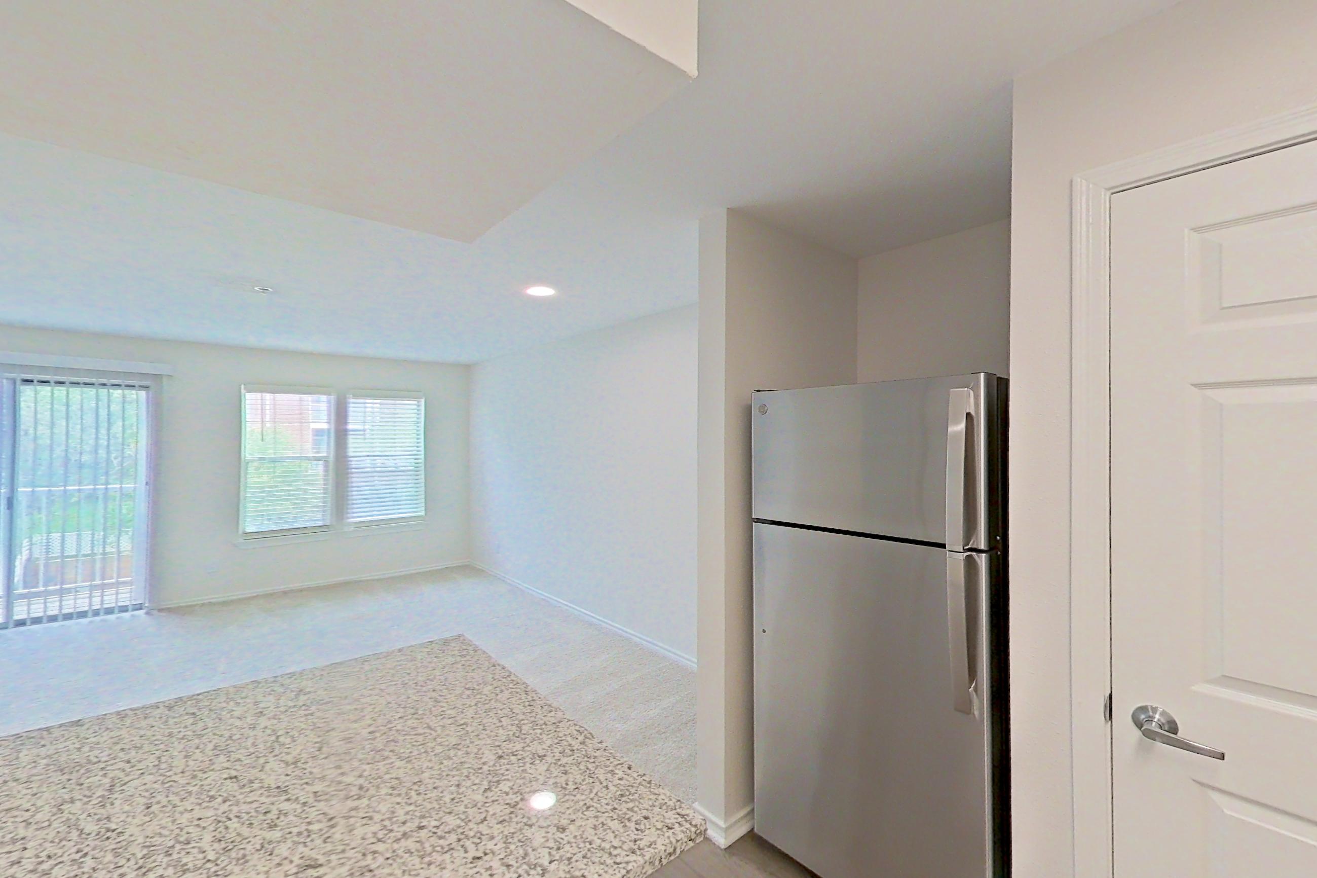Kitchen with dishwasher, electric range, fireplace, light countertops, light stone countertops, light wood-finish flooring, microwave, oven/range, refrigerator, stainless steel appliances, and white appliances, Apartment 5117 at Cortland Van Dorn