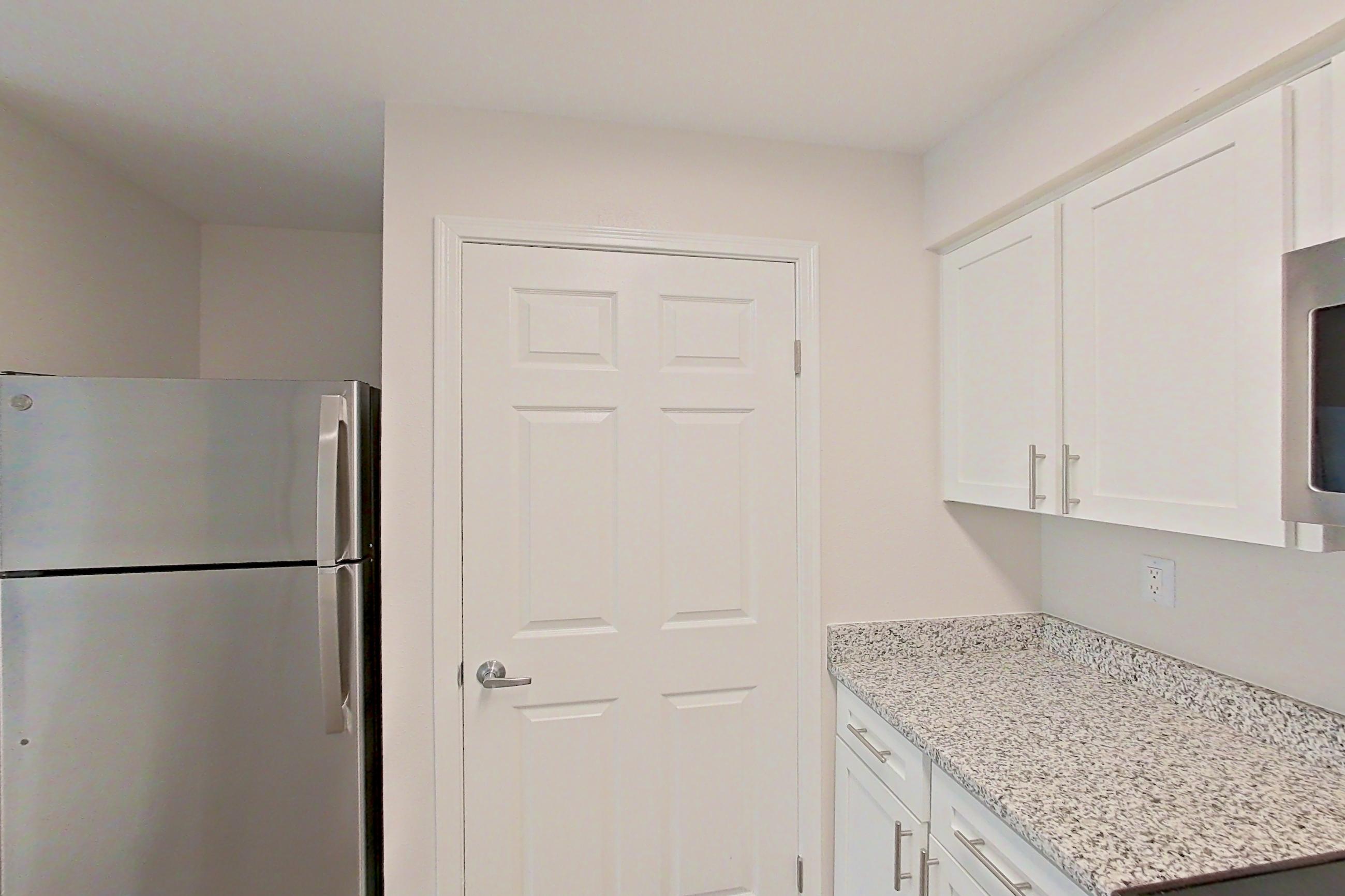 Kitchen with dishwasher, electric range, fireplace, light countertops, light stone countertops, light wood-finish flooring, microwave, oven/range, refrigerator, stainless steel appliances, and white appliances, Apartment 5117 at Cortland Van Dorn