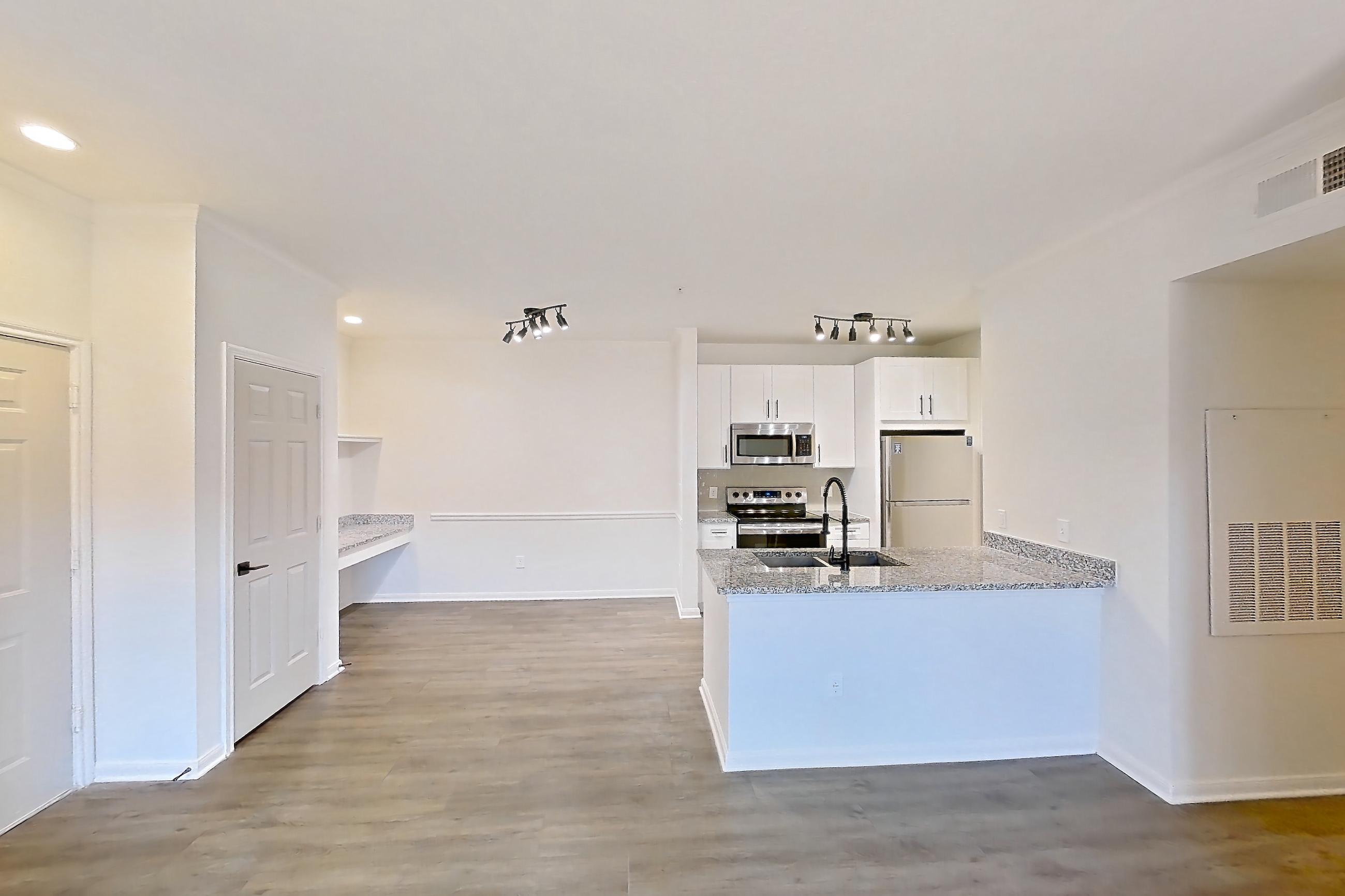 Living room with dark wood-finish flooring, electric range, light stone countertops, oven/range, refrigerator, and stainless steel appliances, Apartment 2206 at Cortland at Twin Creeks