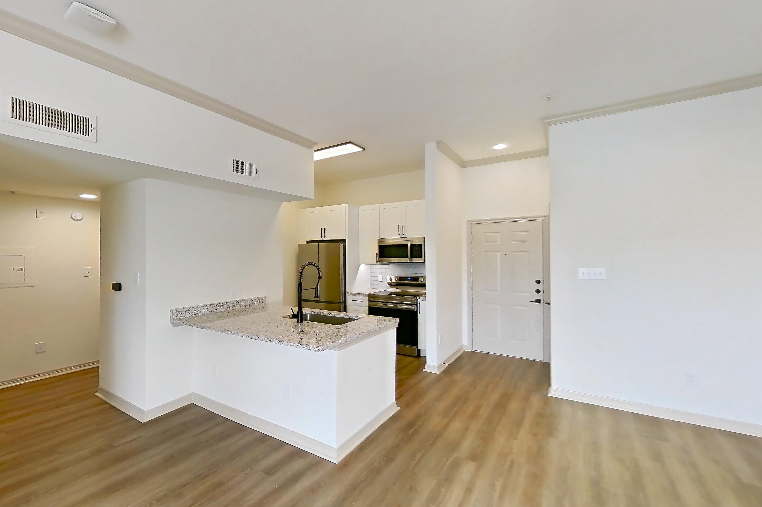 Living room with electric range, light countertops, light wood-finish flooring, oven/range, and stainless steel appliances, Apartment 13309 at Cortland Wortham