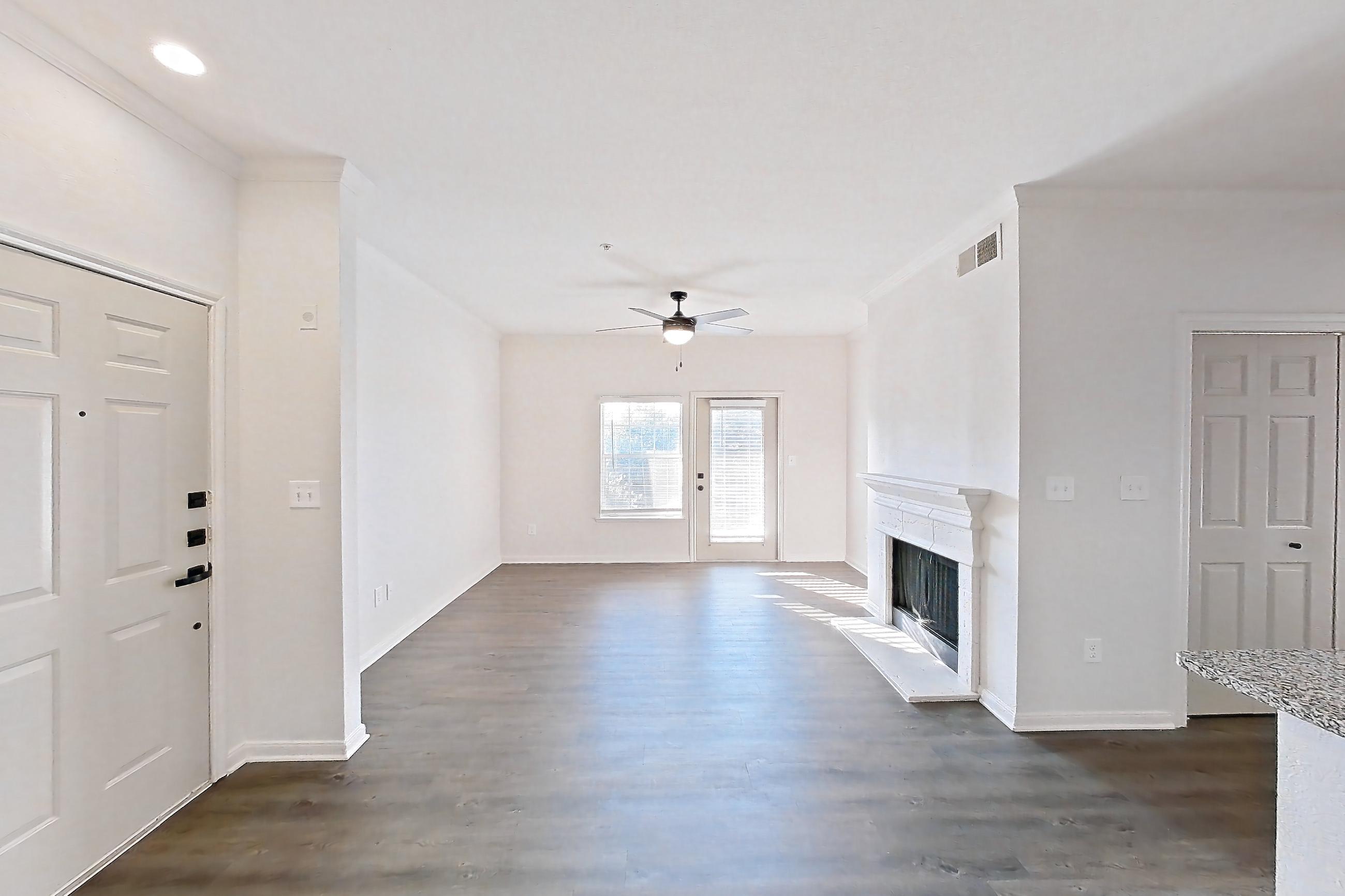 Dining room with dark wood-finish flooring, electric range, fireplace, light stone countertops, microwave, oven/range, and stainless steel appliances, Apartment 2304 at Cortland at Twin Creeks