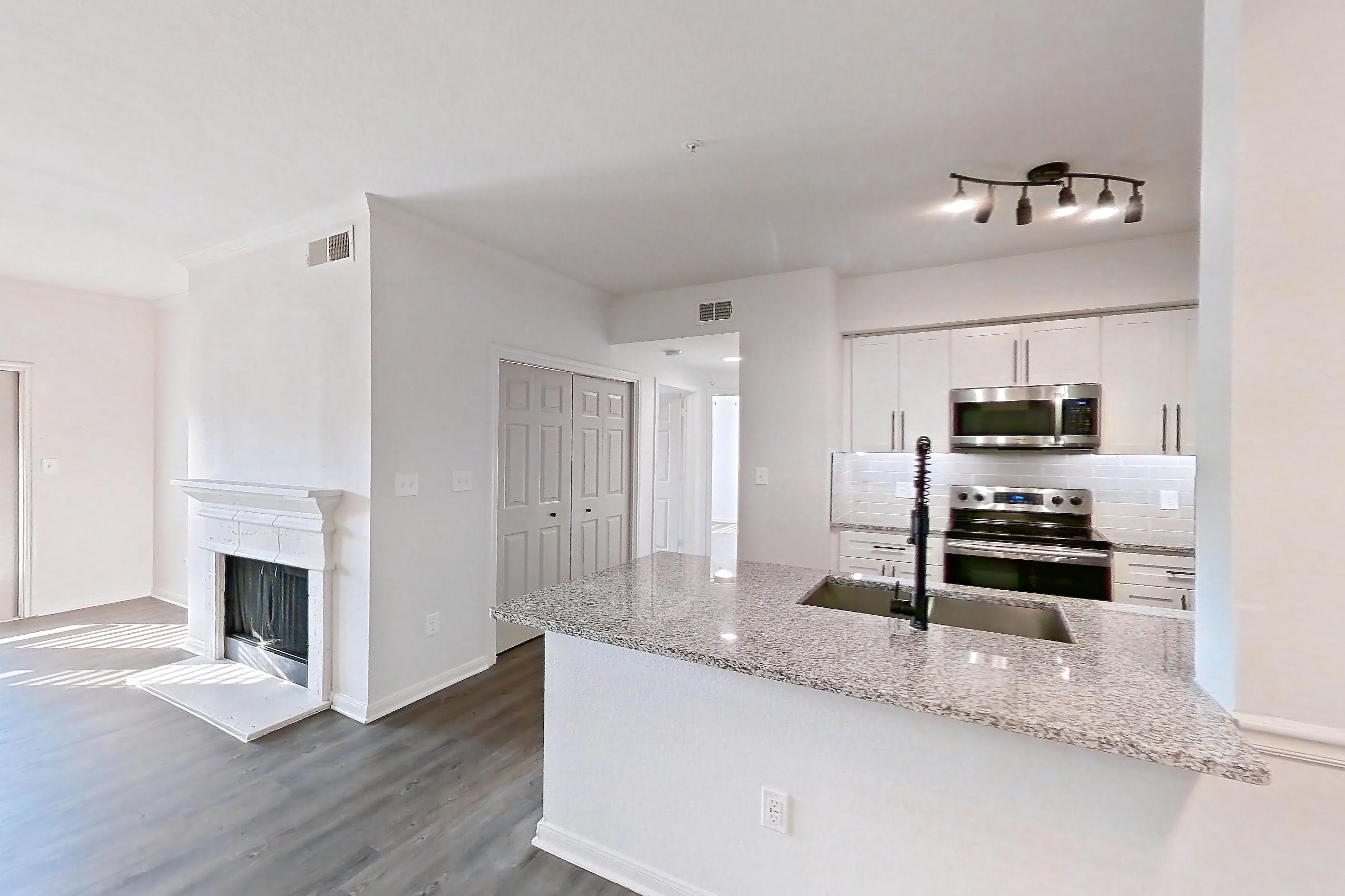 Dining room with dark wood-finish flooring, electric range, fireplace, light stone countertops, microwave, oven/range, and stainless steel appliances, Apartment 2304 at Cortland at Twin Creeks