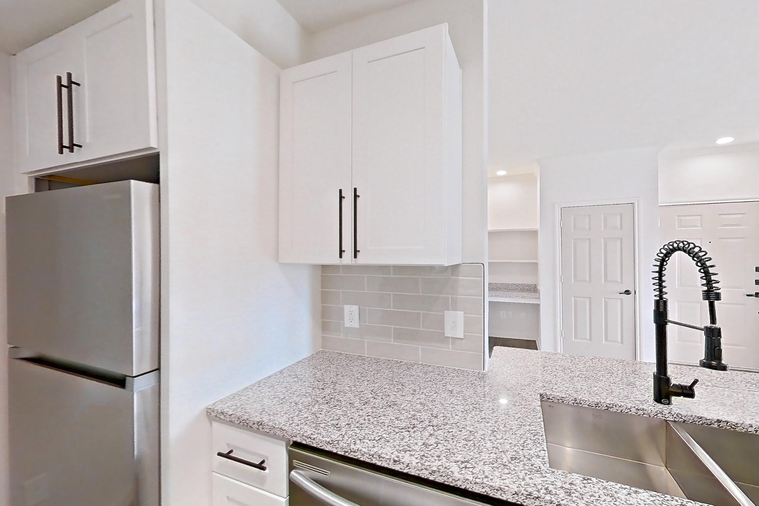 Kitchen with dark wood-finish flooring, dishwasher, electric range, light countertops, light stone countertops, light wood-finish flooring, oven/range, refrigerator, and stainless steel appliances, Apartment 2304 at Cortland at Twin Creeks