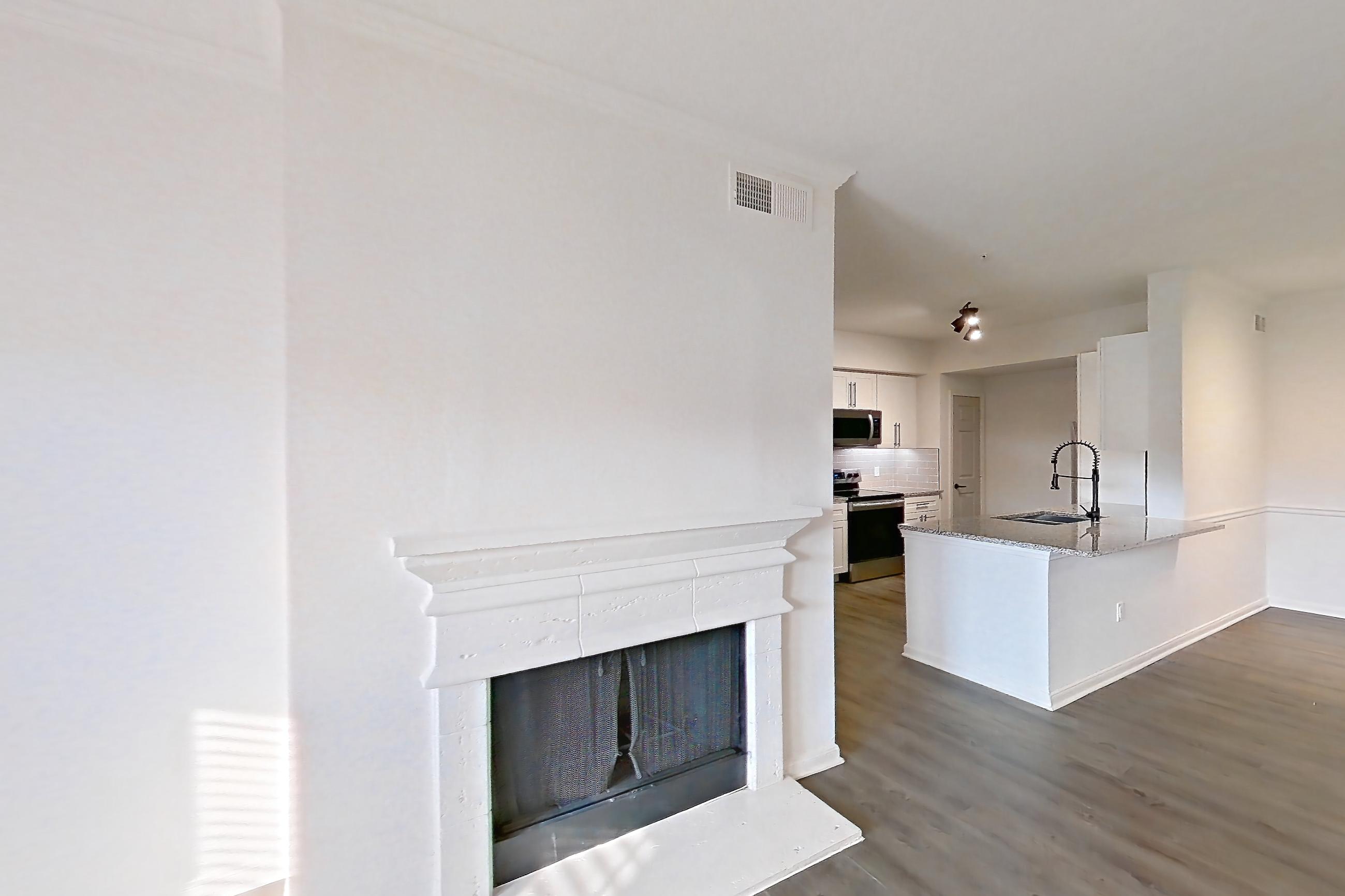 Living room with dark wood-finish flooring, electric range, fireplace, oven/range, and stainless steel appliances, Apartment 2304 at Cortland at Twin Creeks