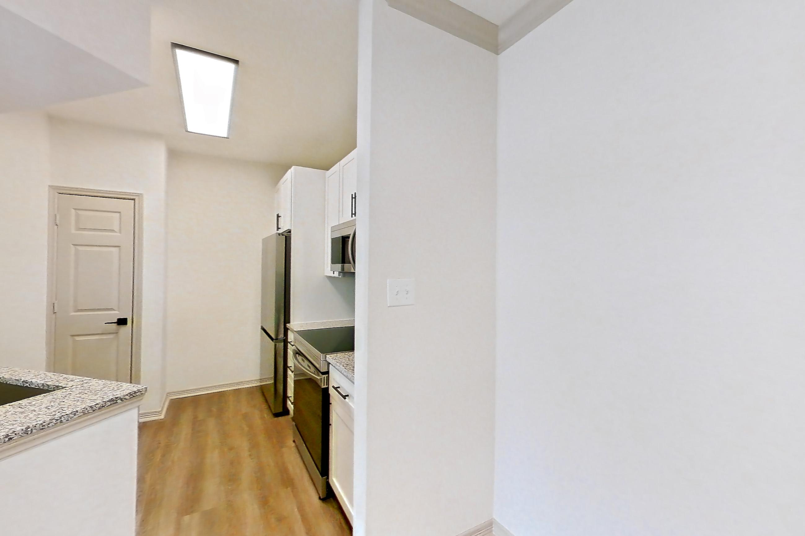 Dining room with electric range, light stone countertops, light wood-finish flooring, microwave, refrigerator, and stainless steel appliances, Apartment 17210 at Cortland Wortham