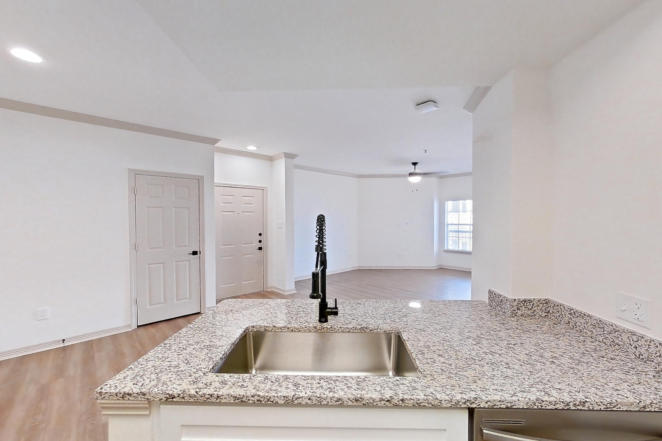 Kitchen with dishwasher, electric range, light countertops, light stone countertops, light wood-finish flooring, microwave, oven/range, and stainless steel appliances, Apartment 17210 at Cortland Wortham