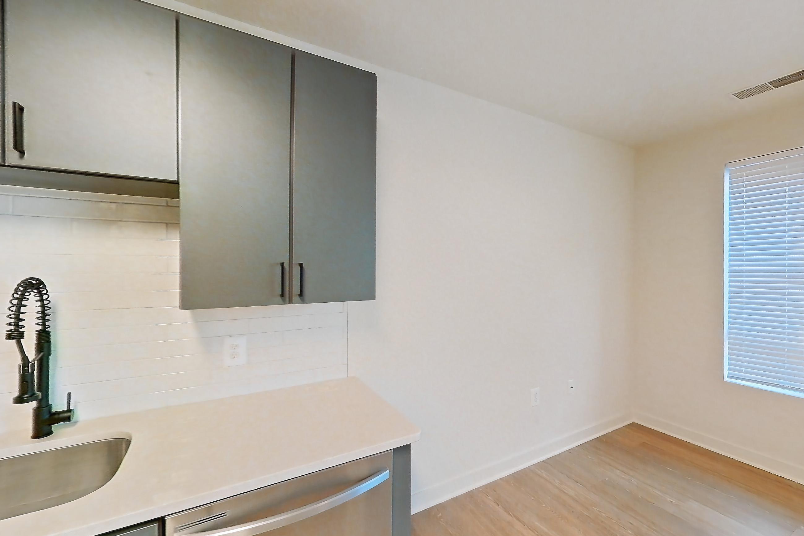 Kitchen with dishwasher, electric range, light countertops, light stone countertops, light wood-finish flooring, microwave, oven/range, refrigerator, and stainless steel appliances, Apartment 423 at Cortland Ballston