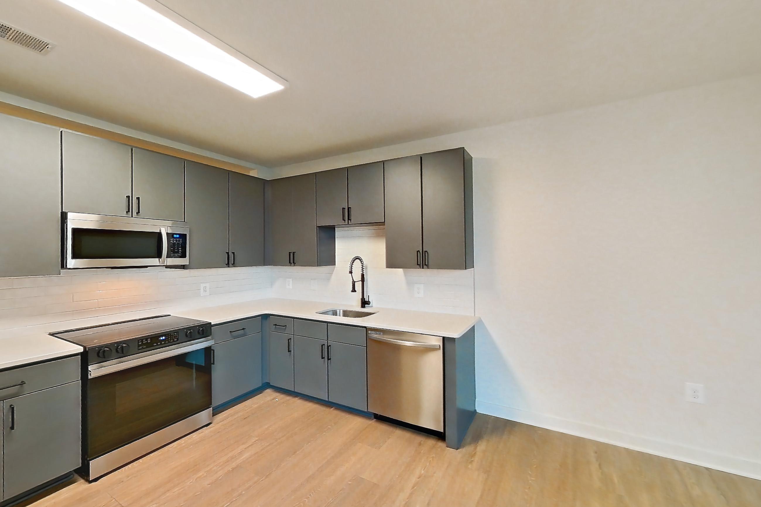 Living room with dishwasher, light stone countertops, light wood-finish flooring, and stainless steel appliances, Apartment 423 at Cortland Ballston