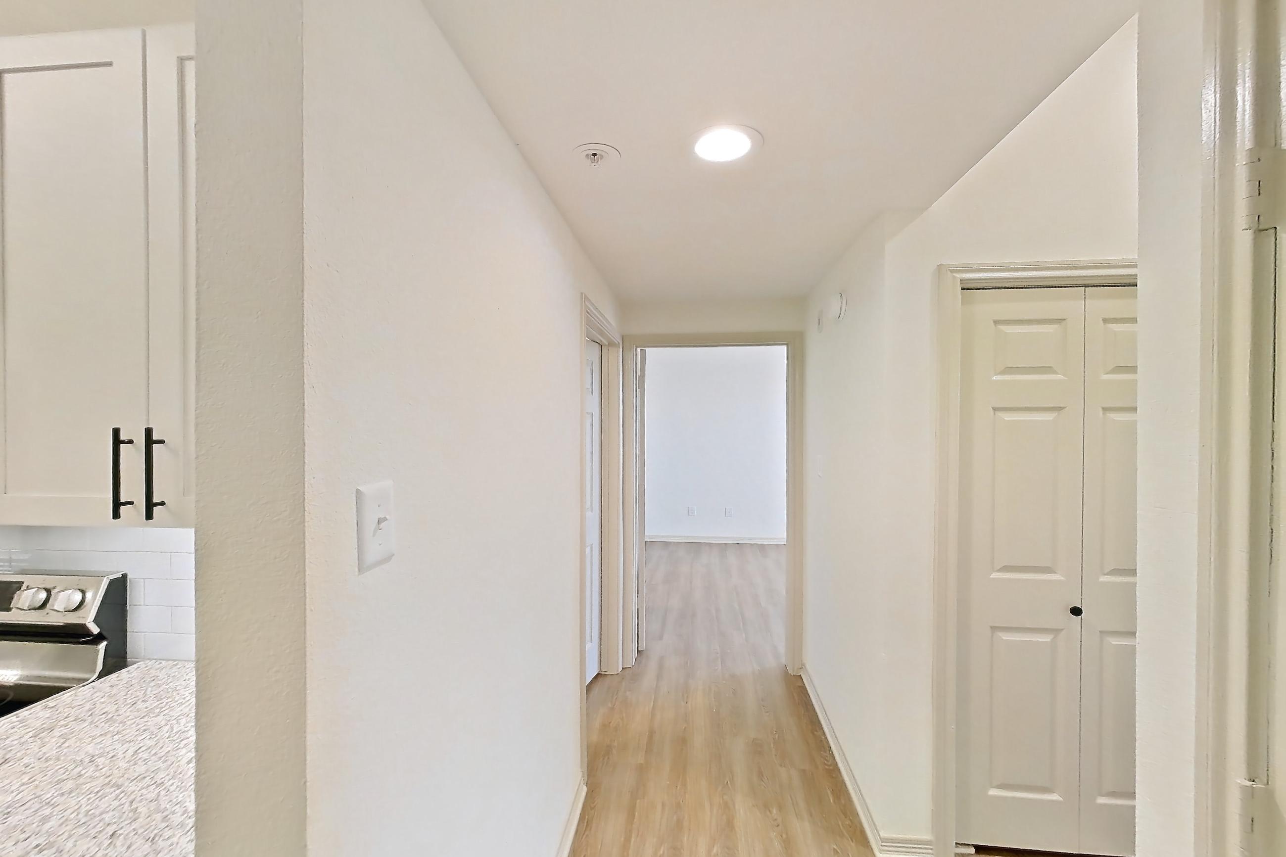 Kitchen space with dishwasher, electric range, light countertops, light stone countertops, light wood-finish flooring, microwave, oven/range, refrigerator, and stainless steel appliances, Apartment 8305 at Cortland Wortham