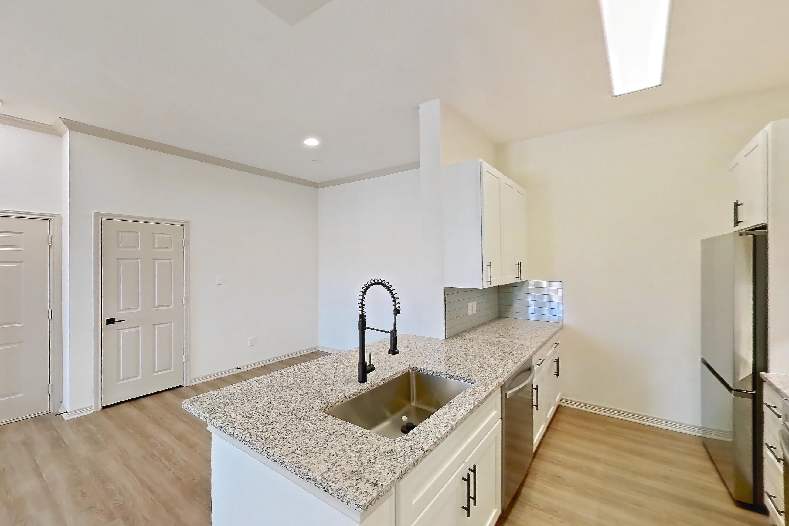 Kitchen space with dishwasher, electric range, light countertops, light stone countertops, light wood-finish flooring, microwave, oven/range, refrigerator, and stainless steel appliances, Apartment 8305 at Cortland Wortham