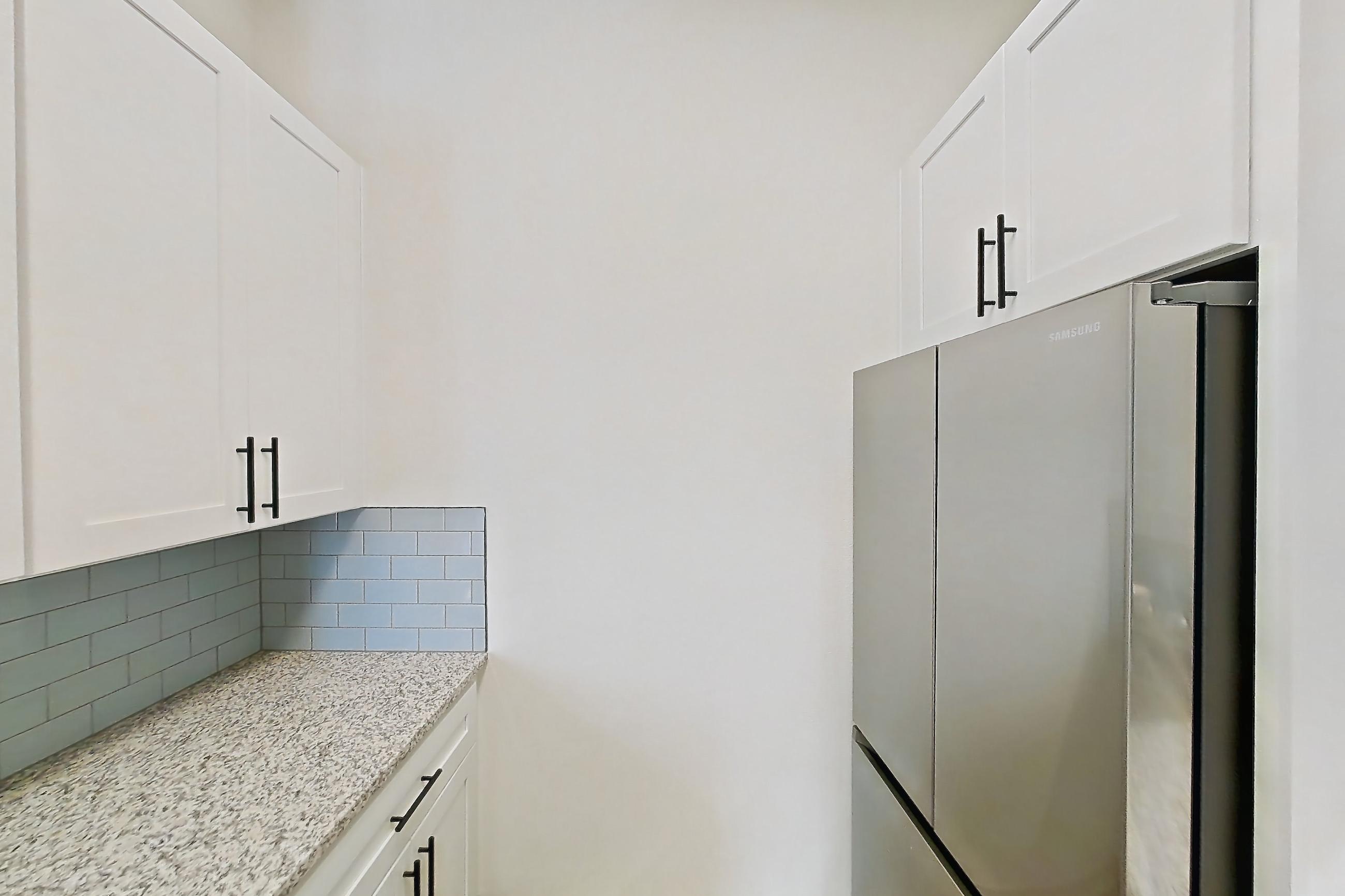 Kitchen with dishwasher, electric range, light countertops, light stone countertops, light wood-finish flooring, microwave, oven/range, refrigerator, and stainless steel appliances, Apartment 8305 at Cortland Wortham