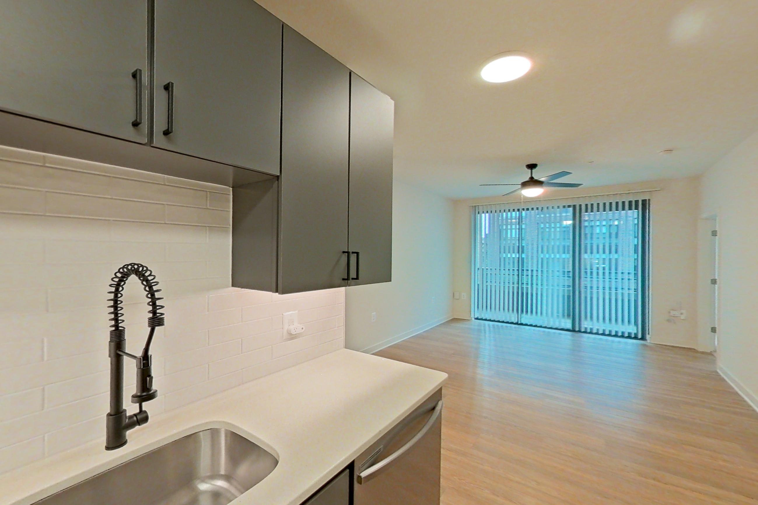 Kitchen with dishwasher, electric range, light countertops, light stone countertops, light wood-finish flooring, microwave, oven/range, and stainless steel appliances, Apartment 207 at Cortland Ballston