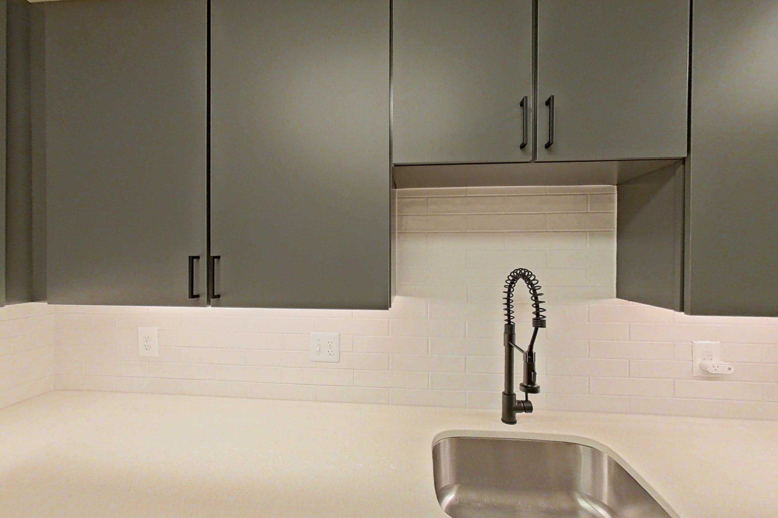 Kitchen with dishwasher, electric range, light countertops, light stone countertops, light wood-finish flooring, microwave, oven/range, and stainless steel appliances, Apartment 207 at Cortland Ballston