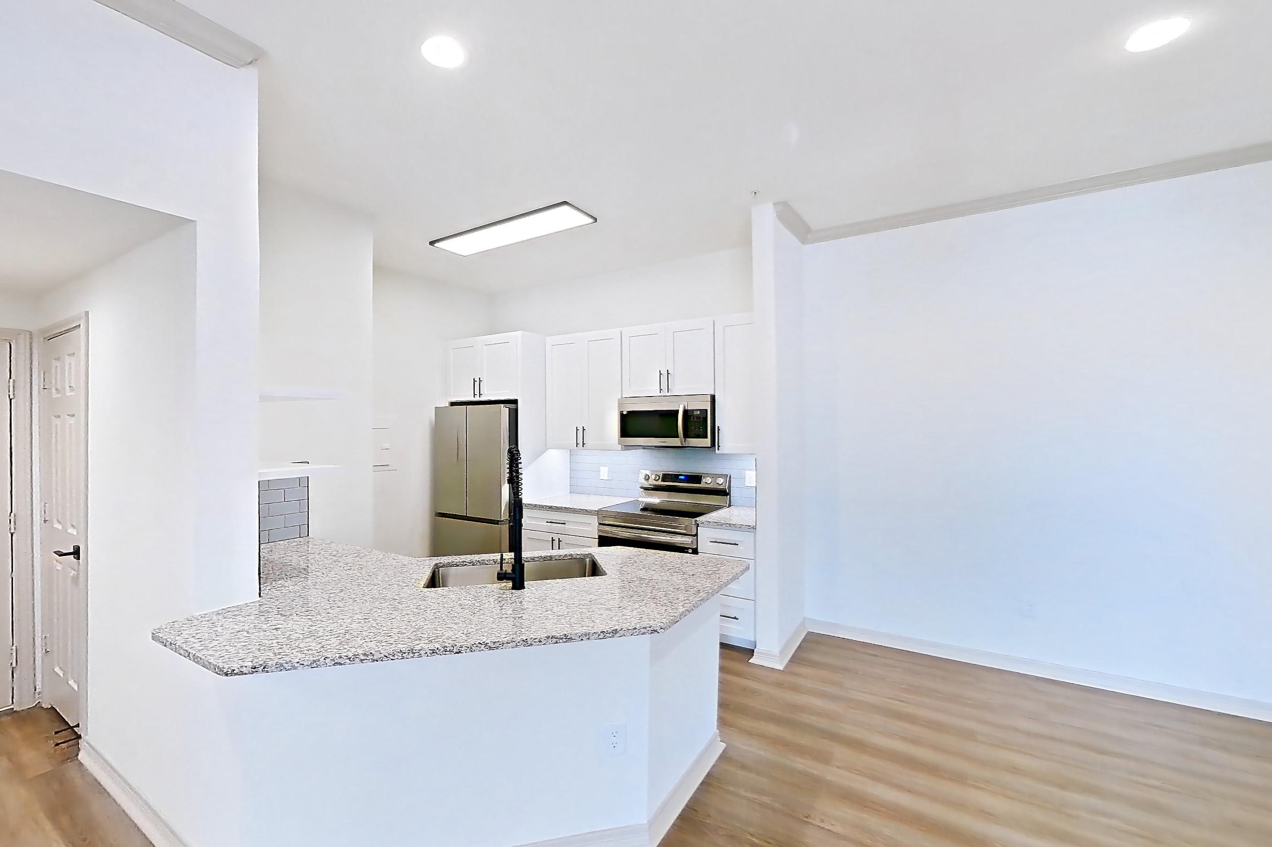 Living space with dark wood-finish flooring, electric range, light stone countertops, light wood-finish flooring, oven/range, refrigerator, and stainless steel appliances, Apartment 7203 at Cortland Wortham