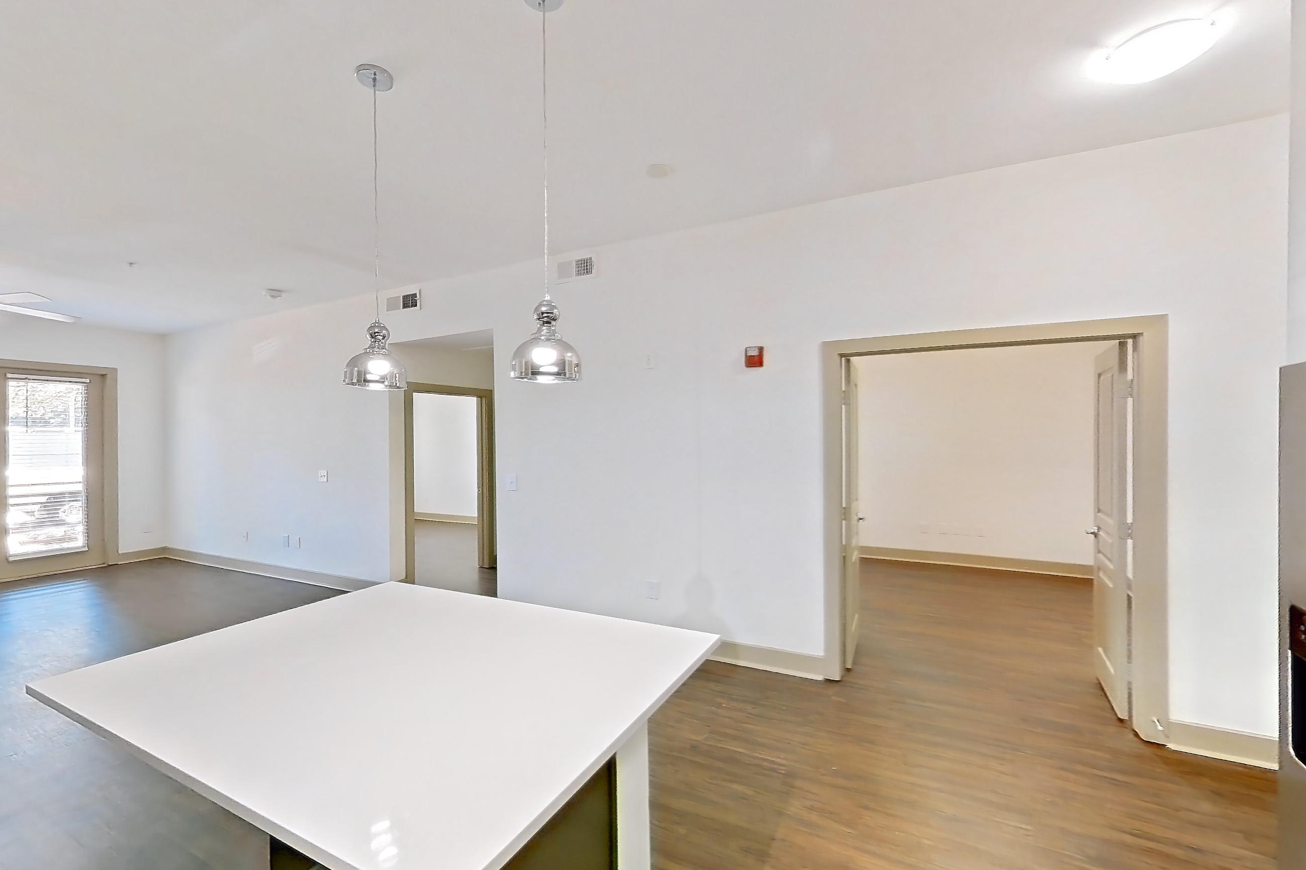 Kitchen with dark wood-finish flooring, dishwasher, light countertops, microwave, refrigerator, stainless steel appliances, and water & ice dispenser, Apartment 3114 at Cortland Galleria