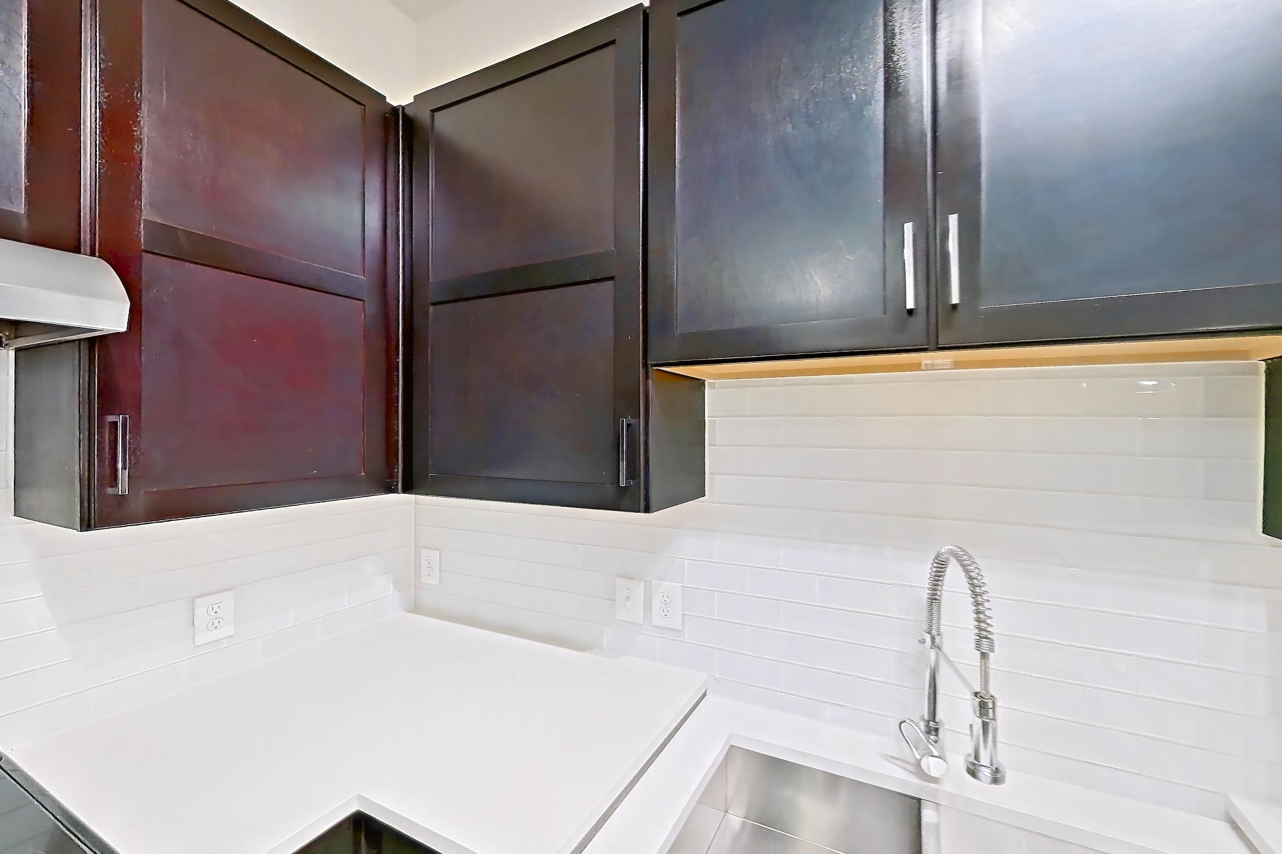 Kitchen with dark wood-finish flooring, dishwasher, light countertops, microwave, refrigerator, stainless steel appliances, and water & ice dispenser, Apartment 3114 at Cortland Galleria