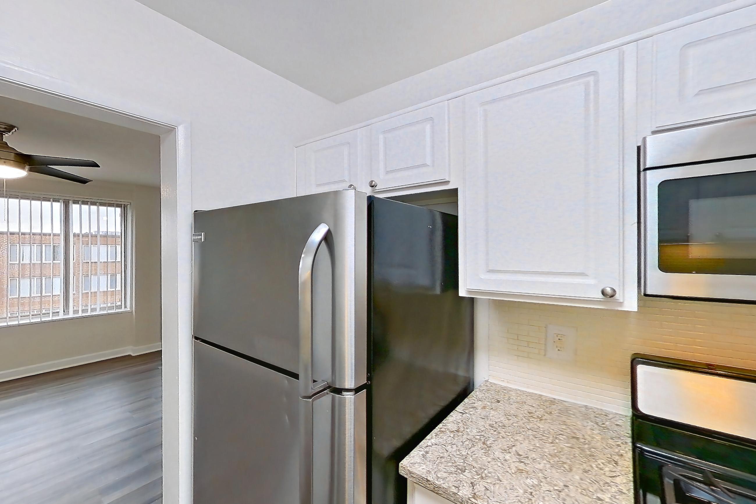 Kitchen with dark wood-finish flooring, dishwasher, gas range, light countertops, light stone countertops, microwave, oven/range, refrigerator, and stainless steel appliances, Apartment S-803 at Cortland on Pike