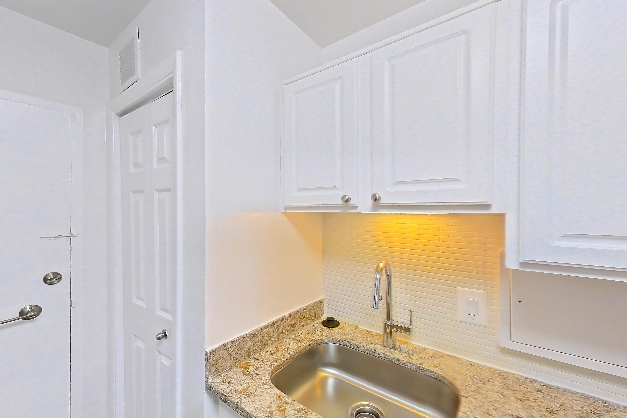 Kitchen with dark wood-finish flooring, dishwasher, gas range, light countertops, light stone countertops, microwave, oven/range, refrigerator, and stainless steel appliances, Apartment S-803 at Cortland on Pike