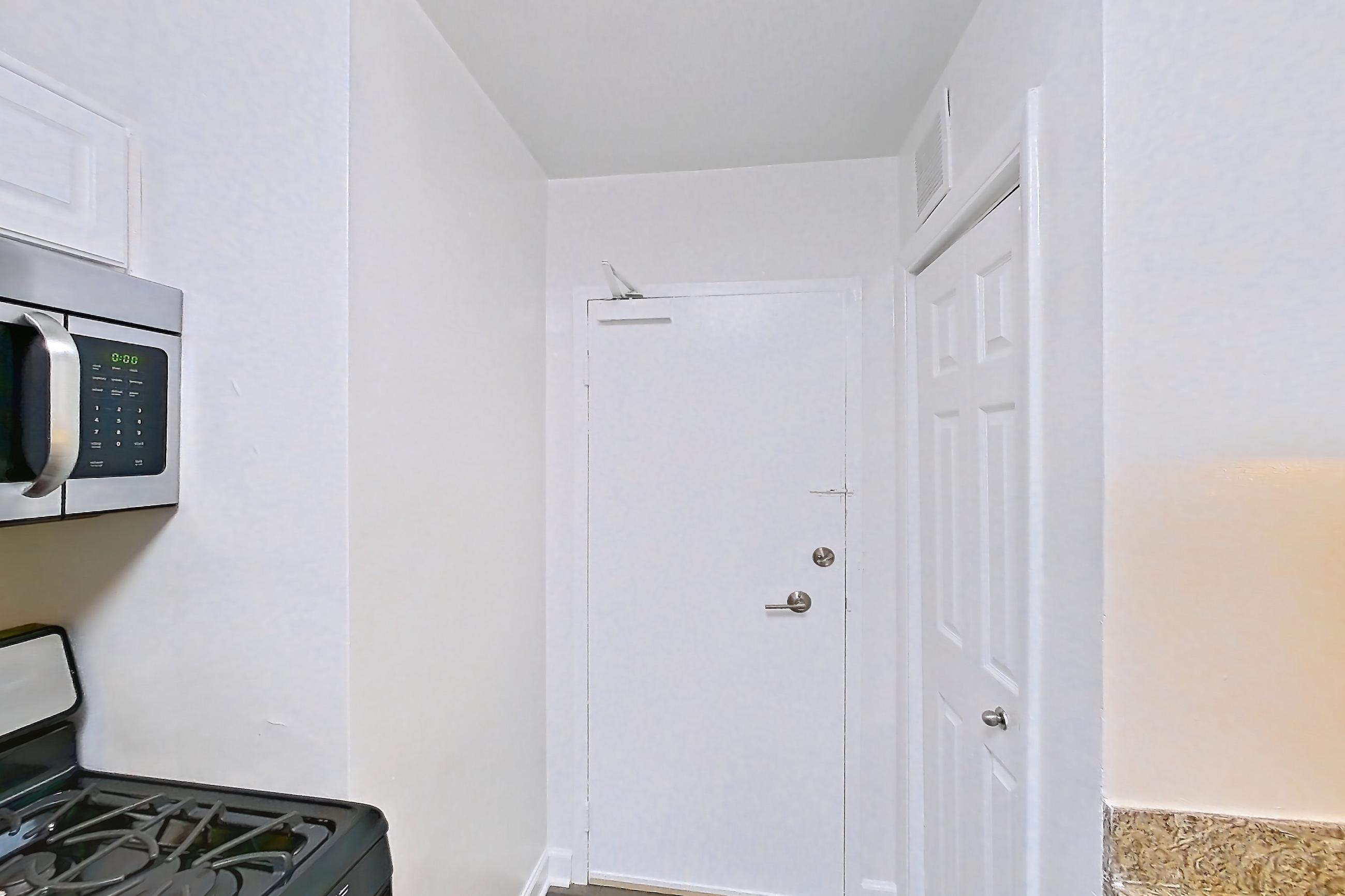 Kitchen with dark wood-finish flooring, dishwasher, gas range, light countertops, light stone countertops, microwave, oven/range, refrigerator, and stainless steel appliances, Apartment S-803 at Cortland on Pike